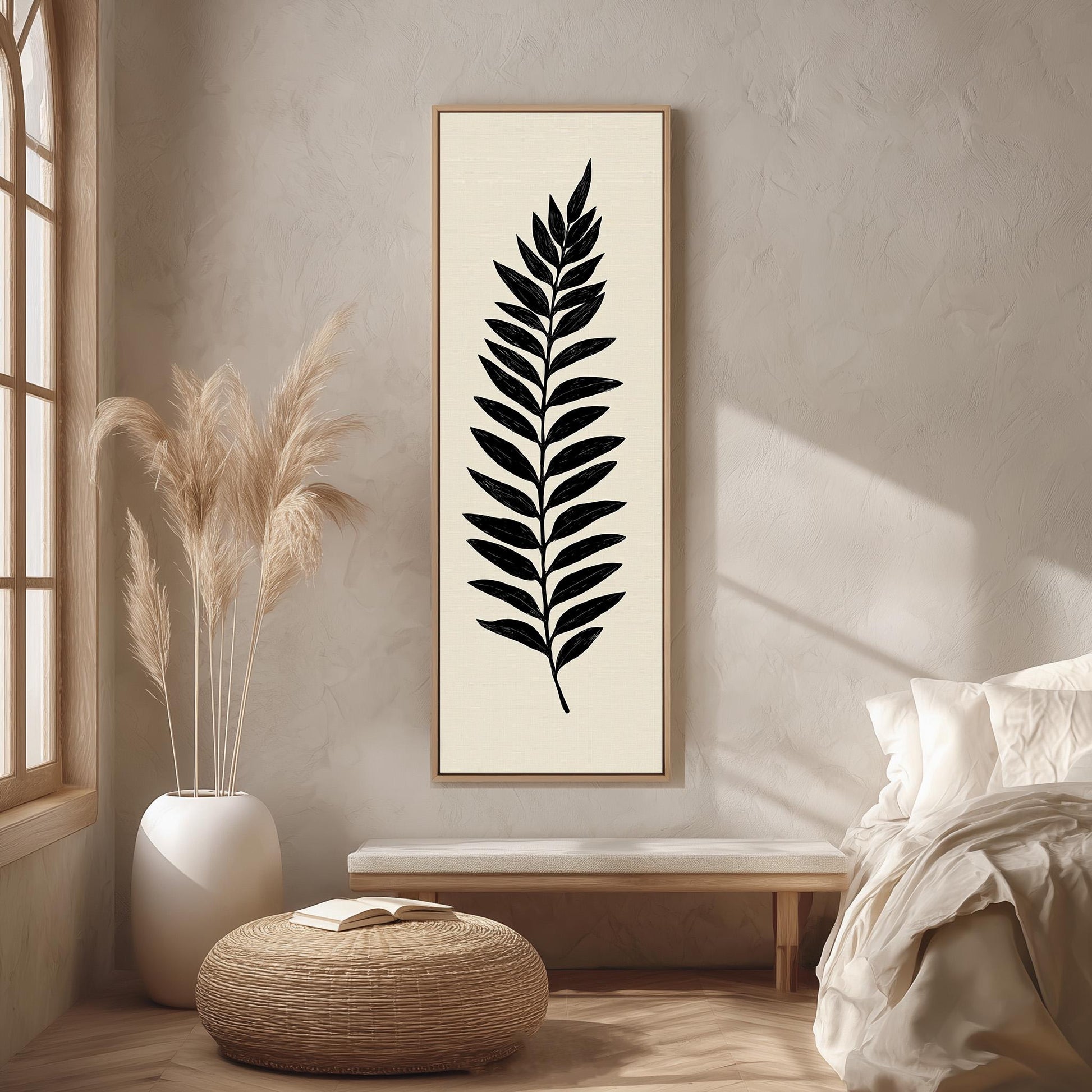 a minimalist bedroom setting with a large black leaf-like artwork hanging on the wall, a white bed with a white pillow, a white vase with dried flowers, and a woven ottoman.