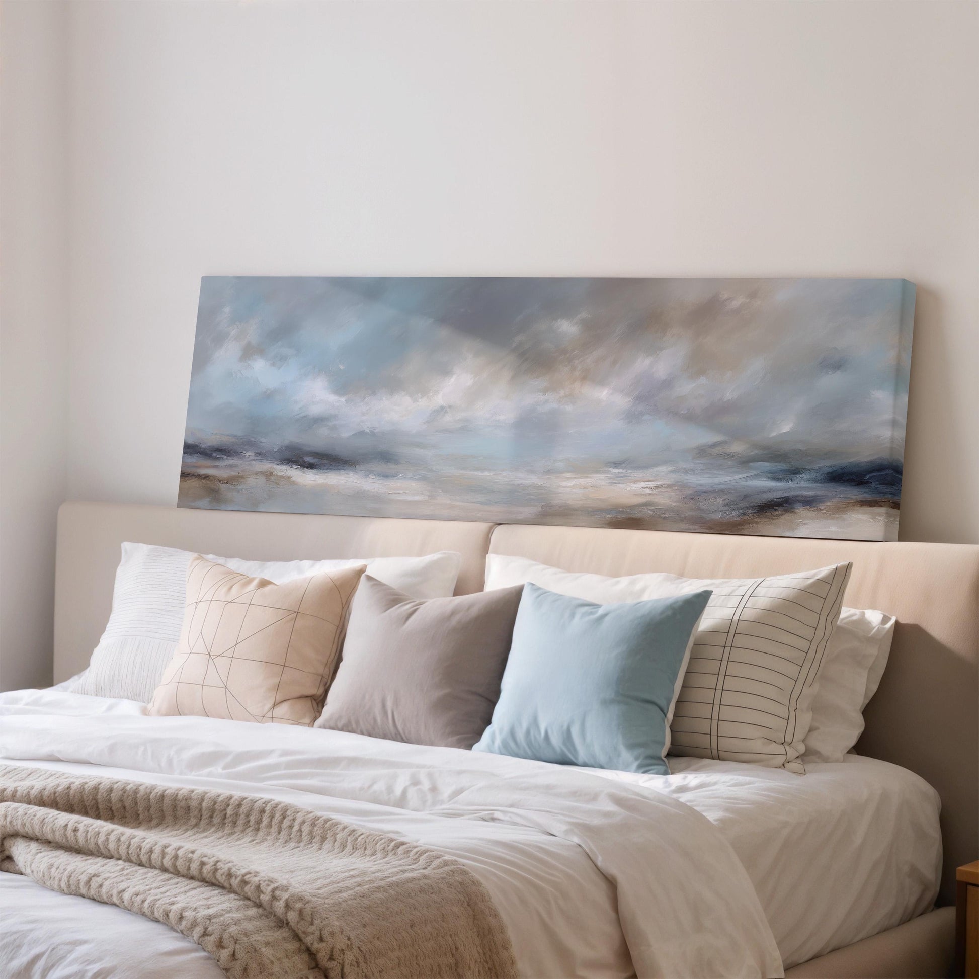 a cozy bedroom with a large bed adorned with white linens and a variety of colorful throw pillows. Above the bed, there is a painting of a cloudy sky, adding a touch of artistry to the room's decor.