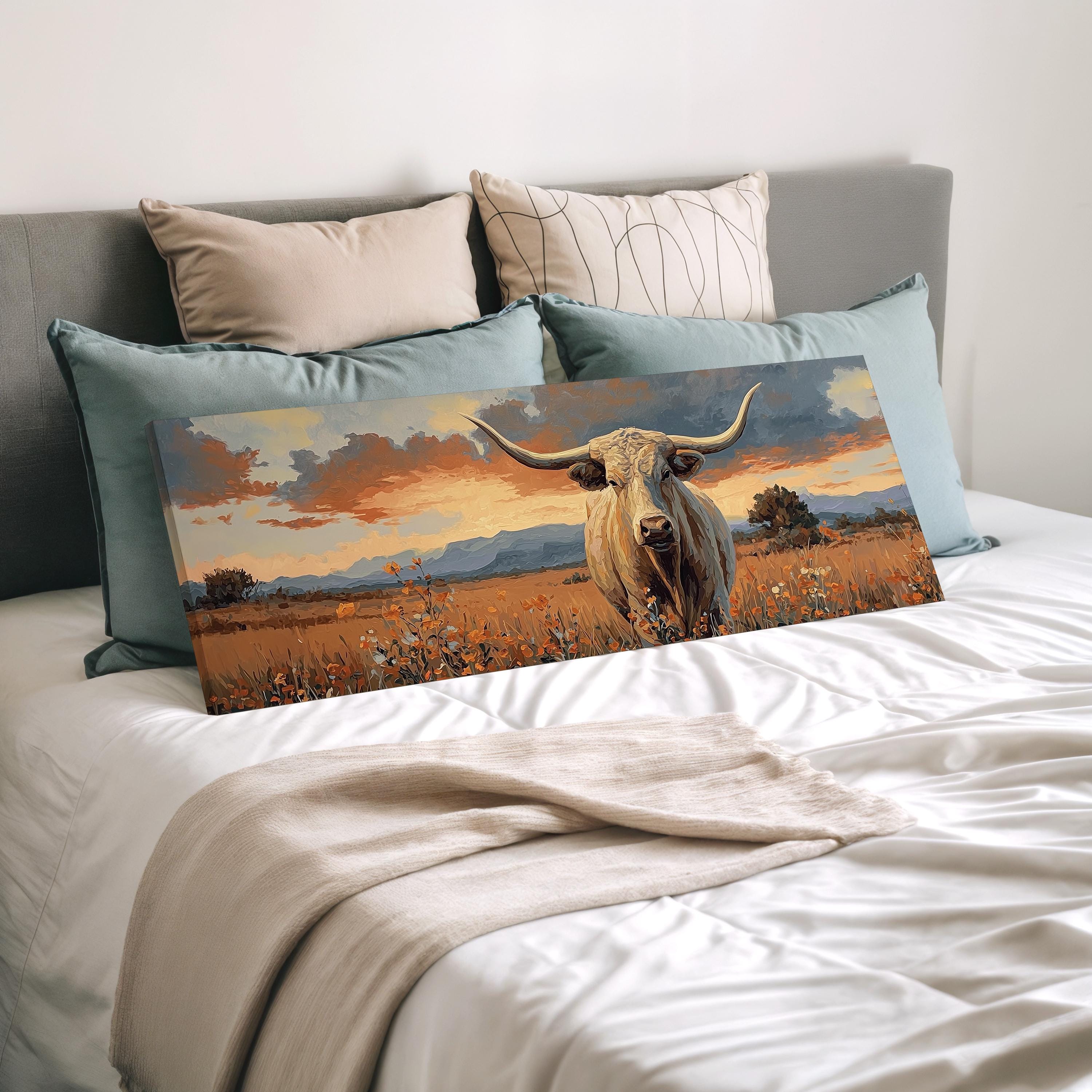 a large canvas print of a bull with horns, displayed on a bed with pillows.