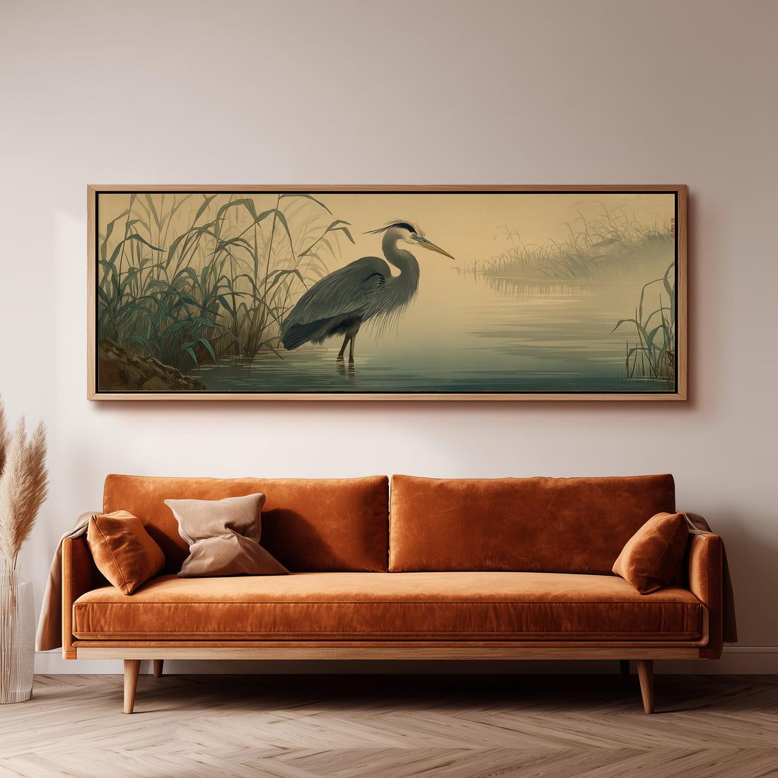 a large painting of a heron standing in a body of water, hanging on a wall above a brown sofa.