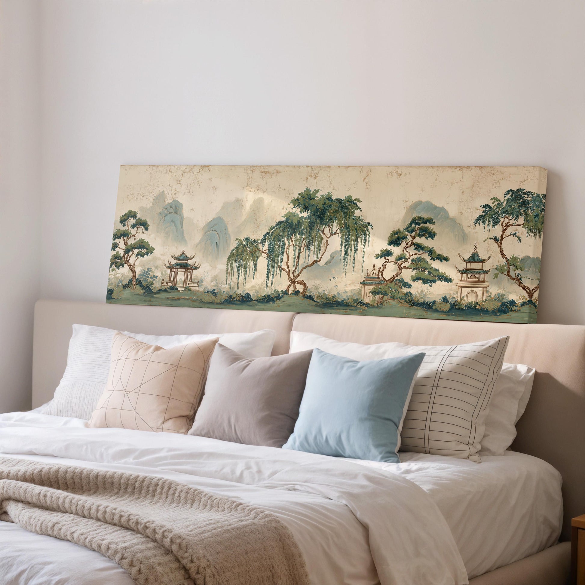 a large painting of a serene landscape with mountains, trees, and pagodas on the wall above a bed with white linens and pillows.