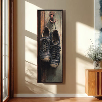 A pair of worn black shoes hanging on a wooden door, with a red hook and chain attached to the door.