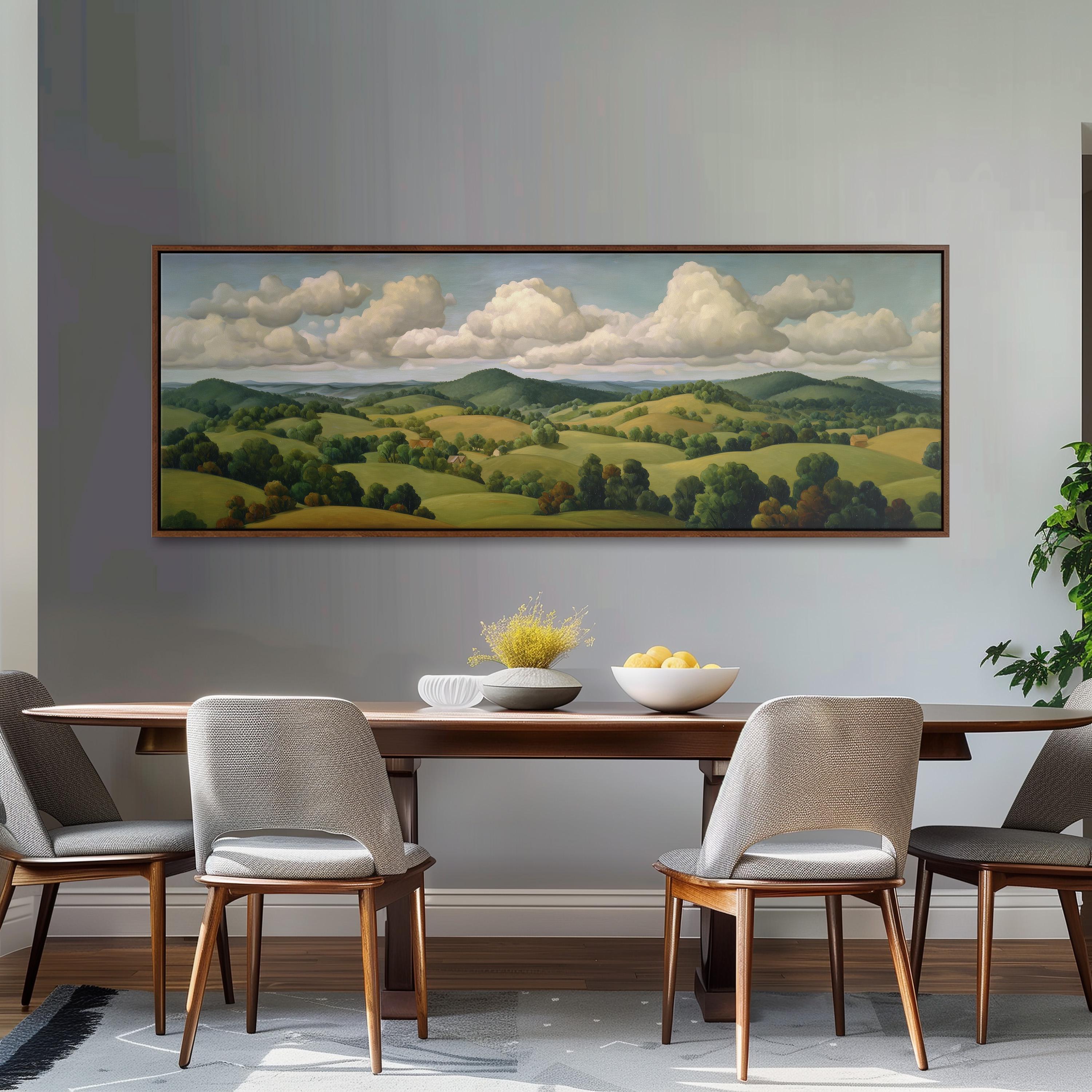 a large landscape painting hanging on a wall above a wooden dining table with four chairs. The painting depicts a serene countryside scene with rolling hills, trees, and a cloudy sky.
