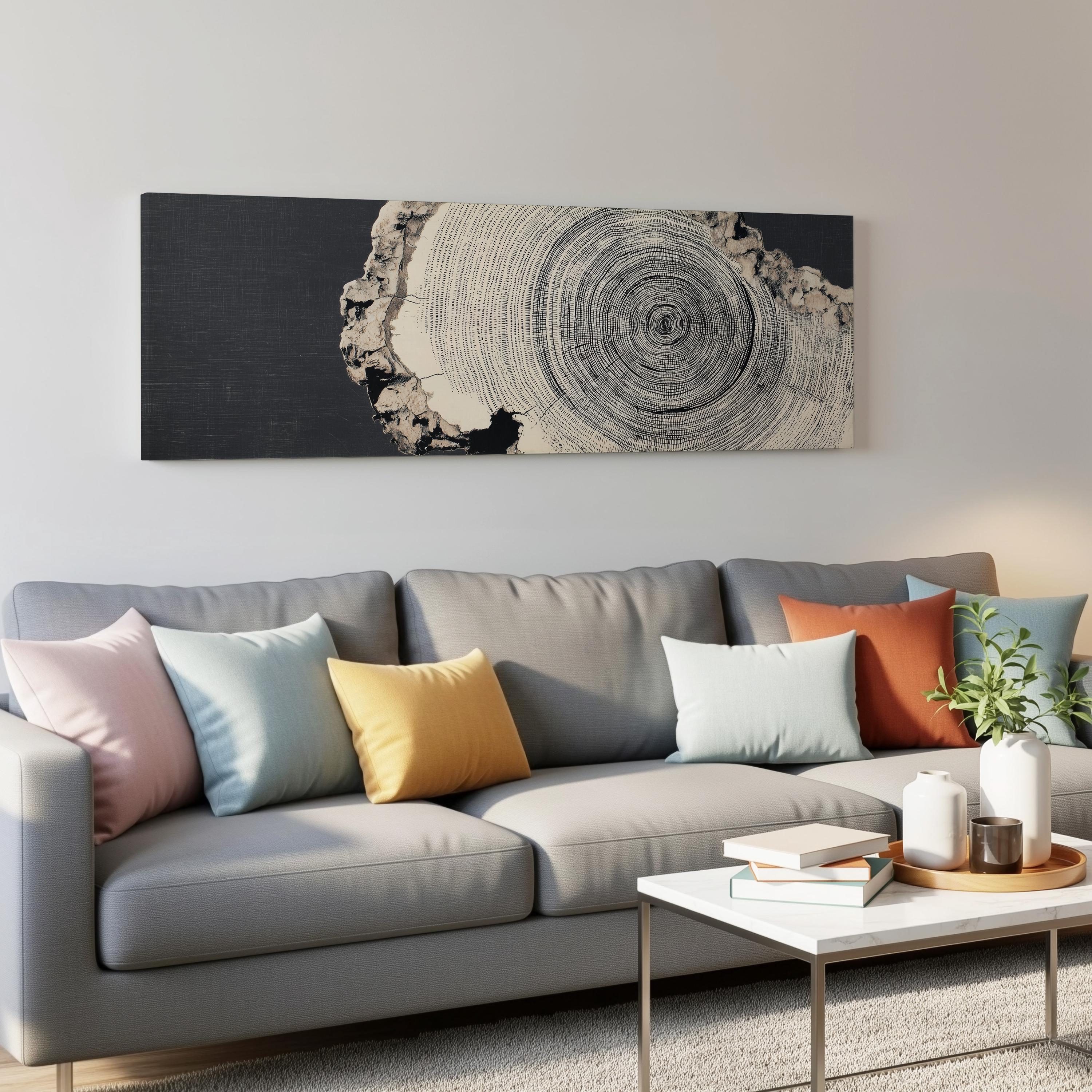 a modern living room with a gray sofa adorned with colorful throw pillows, a white coffee table, and a large black and white tree trunk artwork hanging on the wall above the sofa.