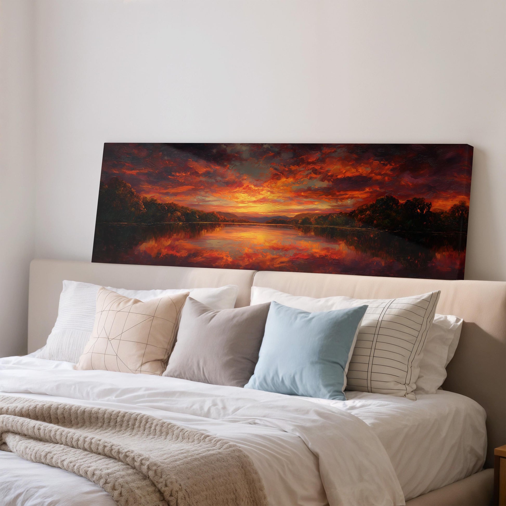 a large, framed painting of a sunset landscape hanging on a wall above a bed with white bedding and pillows.