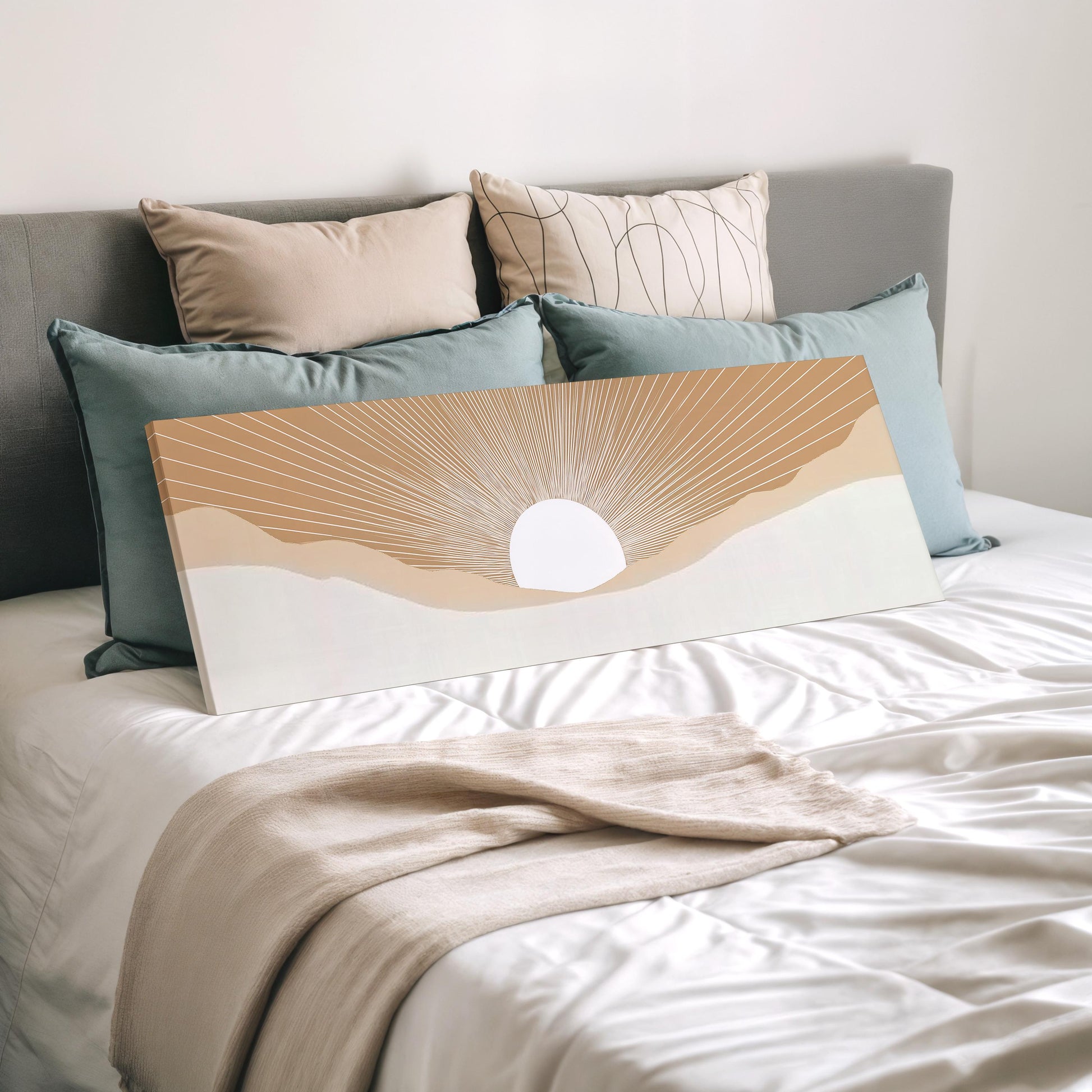 a bed with a white comforter and a large canvas print of a sunrise or sunset design on it. The bed is surrounded by multiple pillows, creating a cozy and inviting atmosphere.