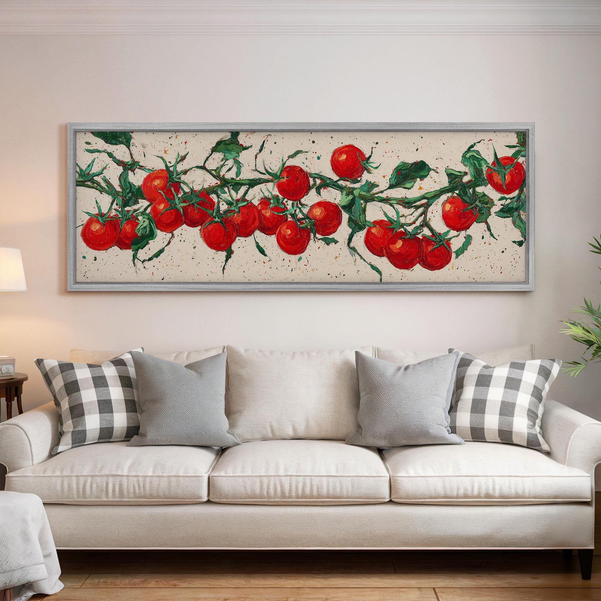 a large painting of red tomatoes hanging on the wall above a white couch with gray and white pillows.