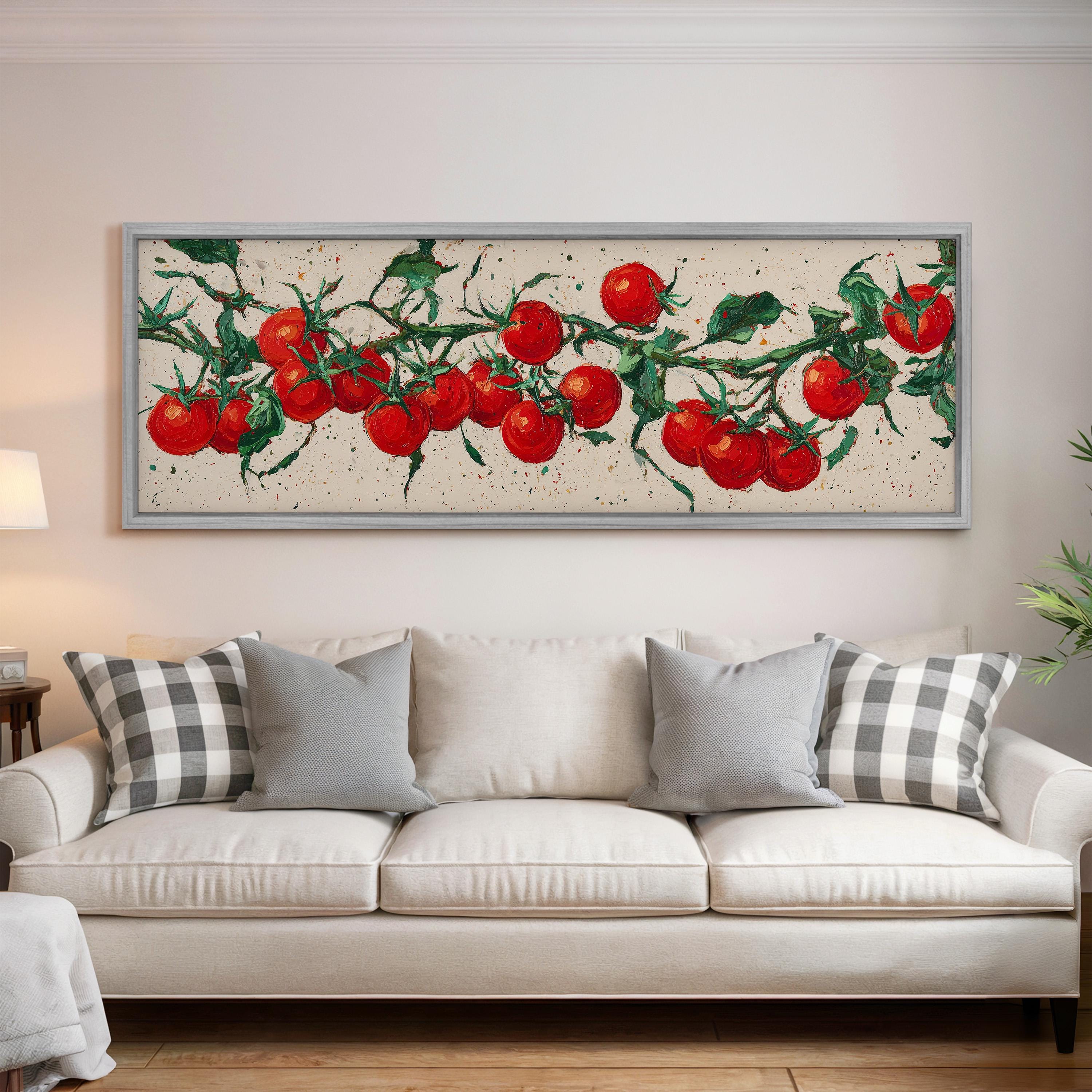 a large painting of red tomatoes hanging on the wall above a white couch with gray and white pillows.