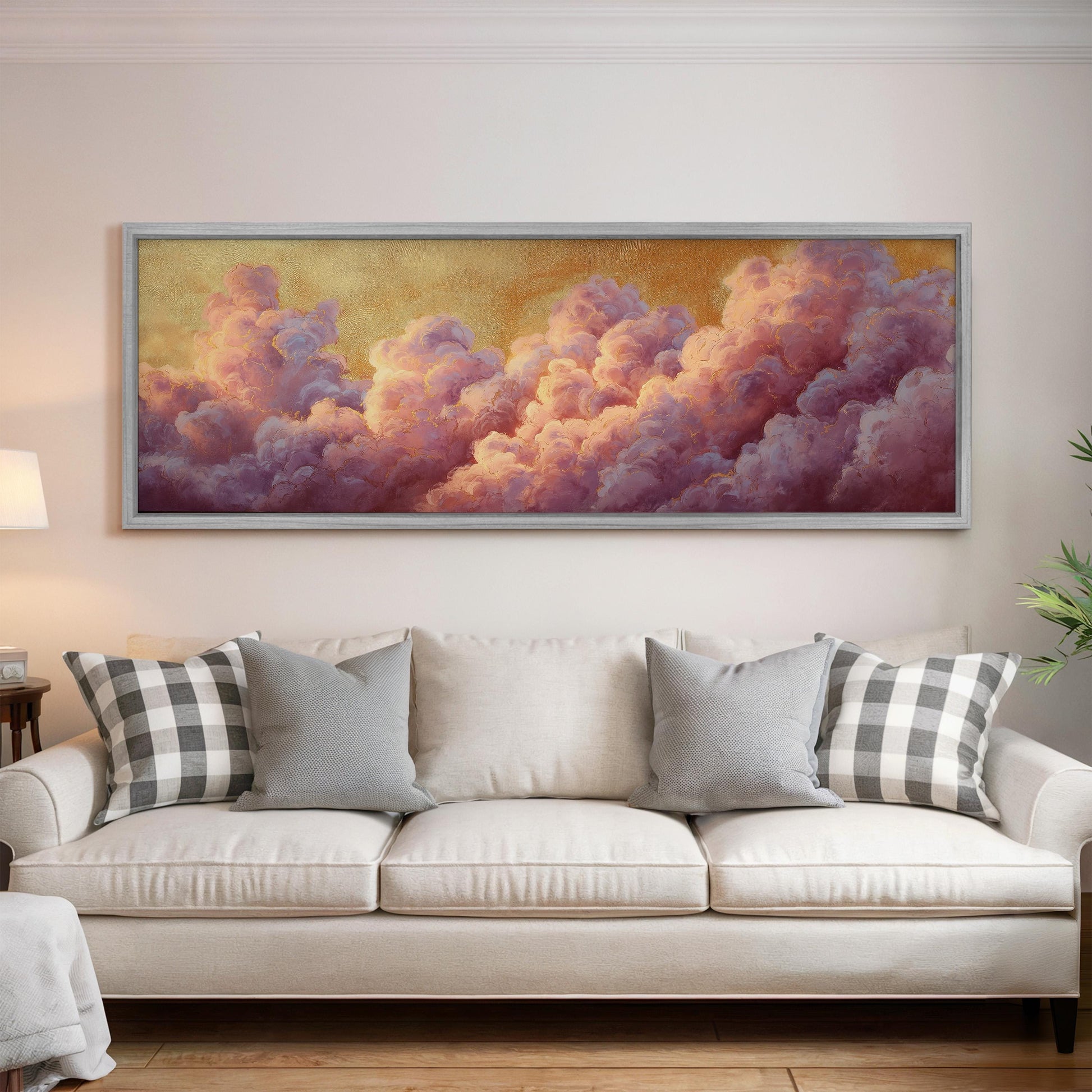 a large, framed painting of clouds hanging on a wall above a white couch with gray and white plaid throw pillows.