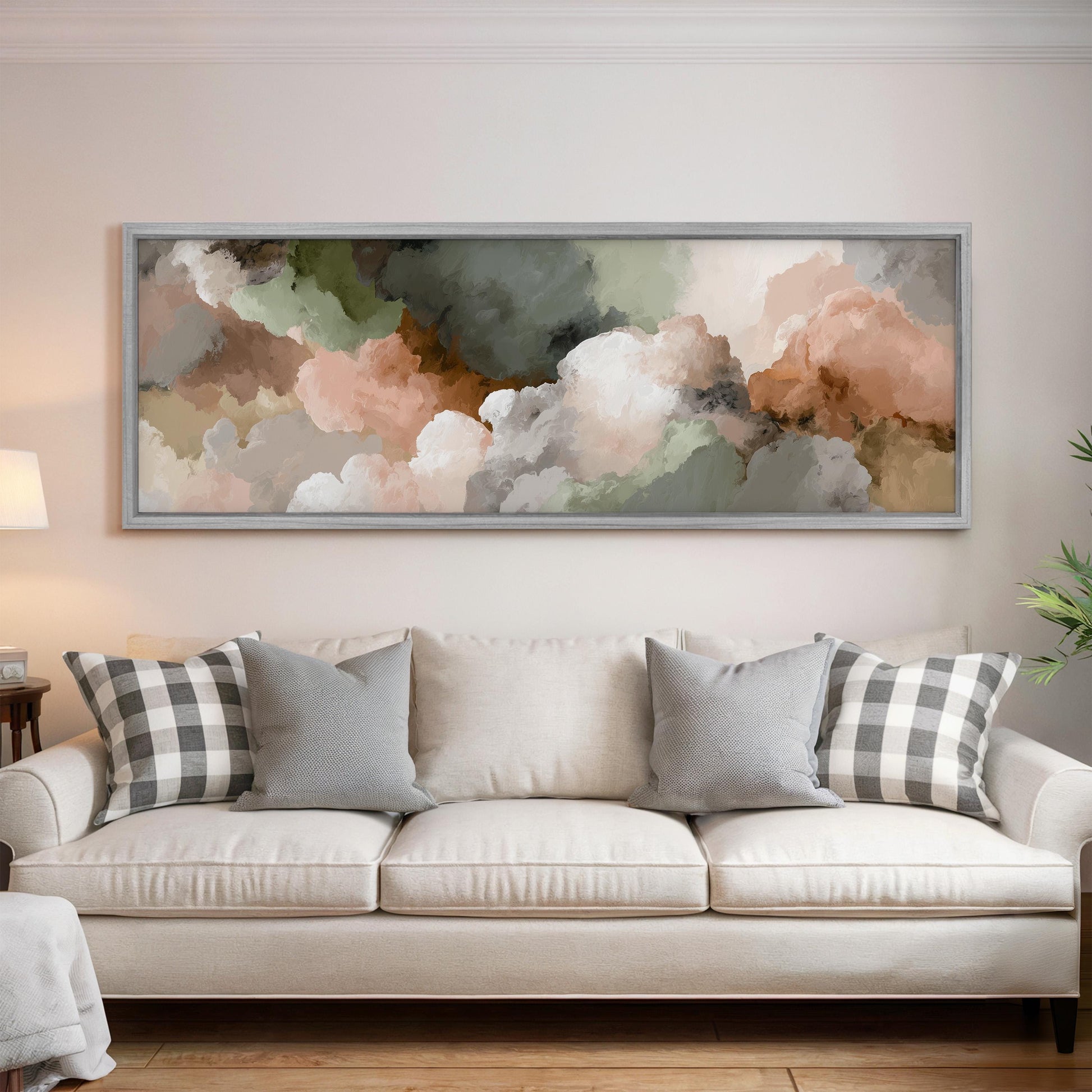 a large, framed painting of clouds hanging above a white couch with gray and white plaid throw pillows.