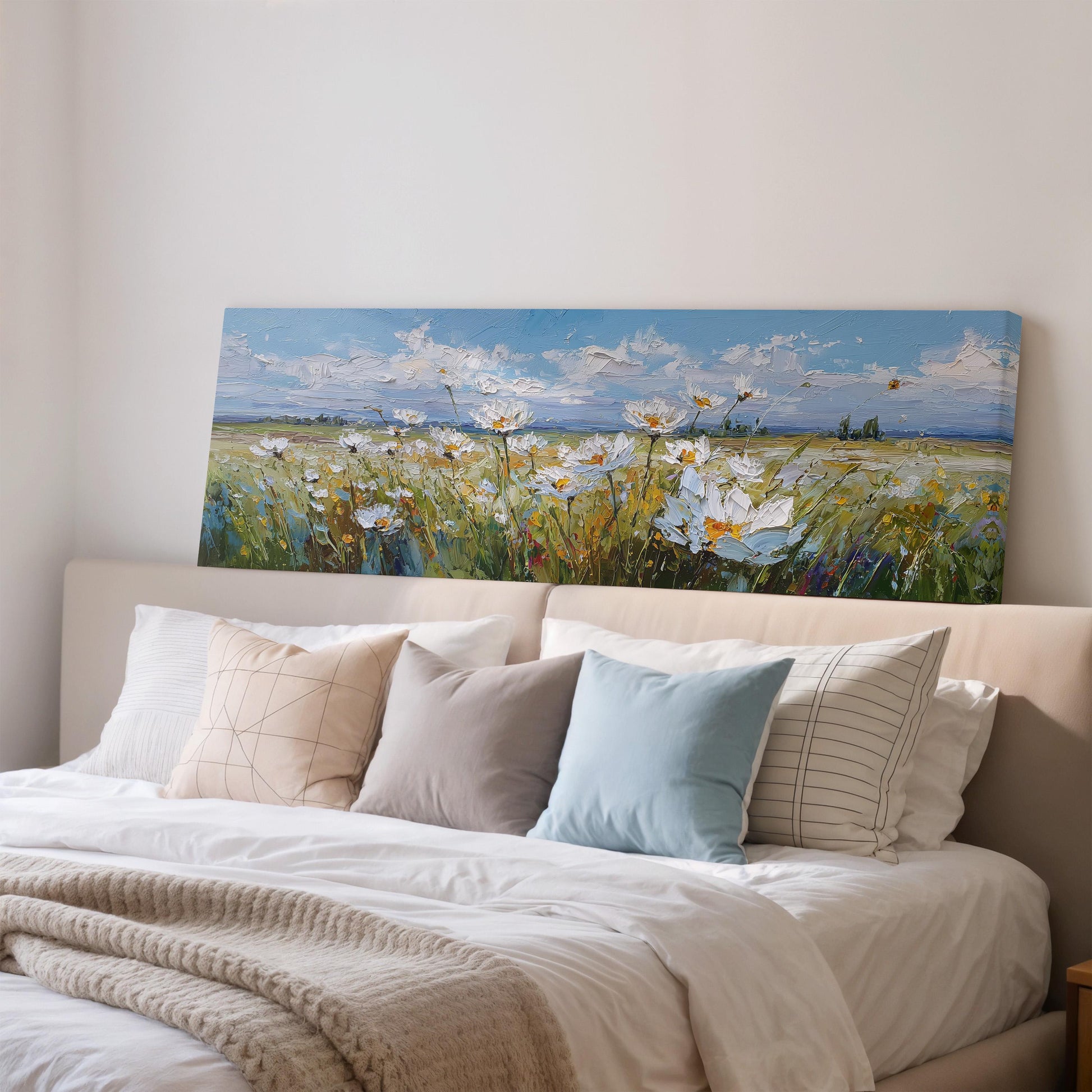a large painting of a field of flowers hanging above a bed with white sheets and pillows.