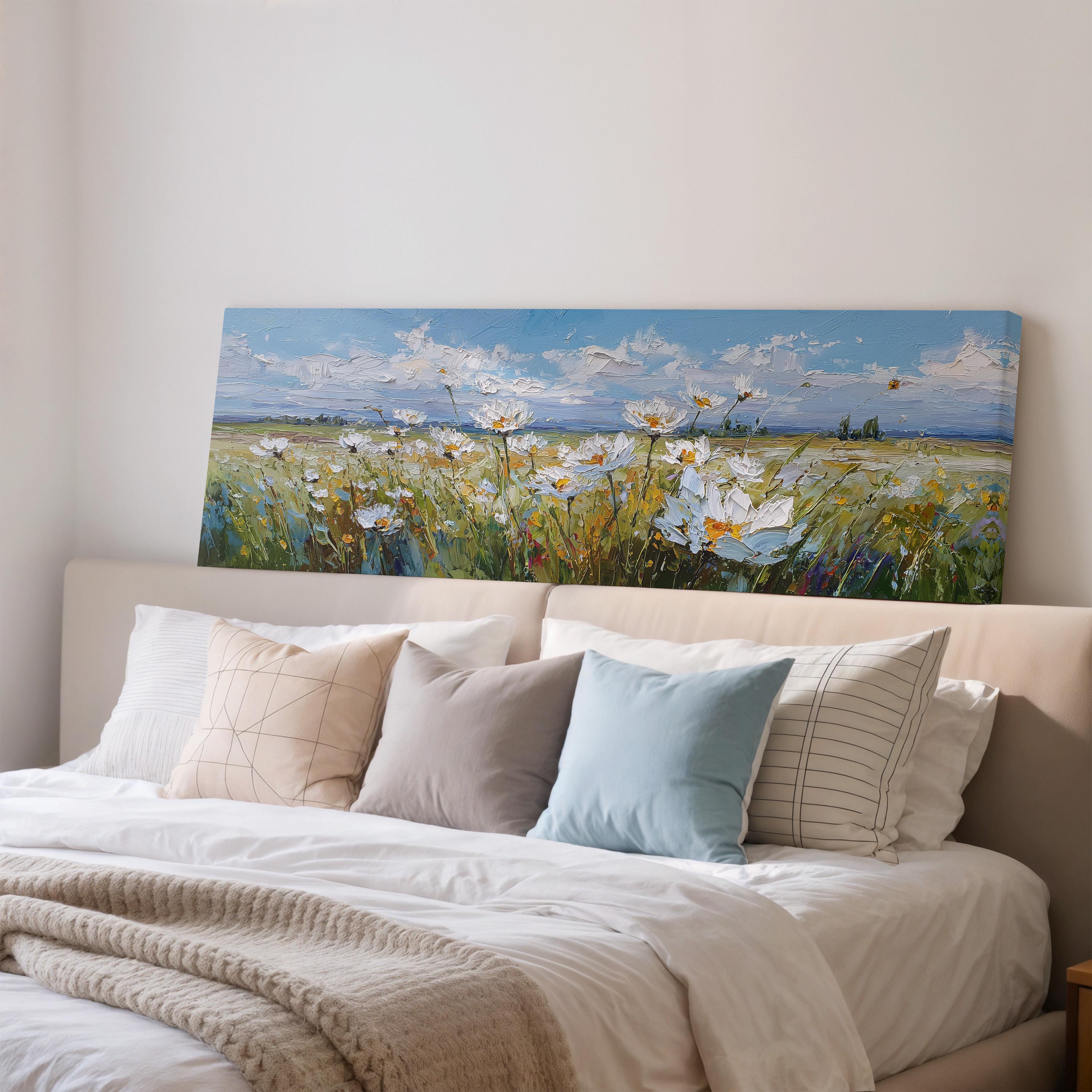 a large painting of a field of flowers hanging above a bed with white sheets and pillows.