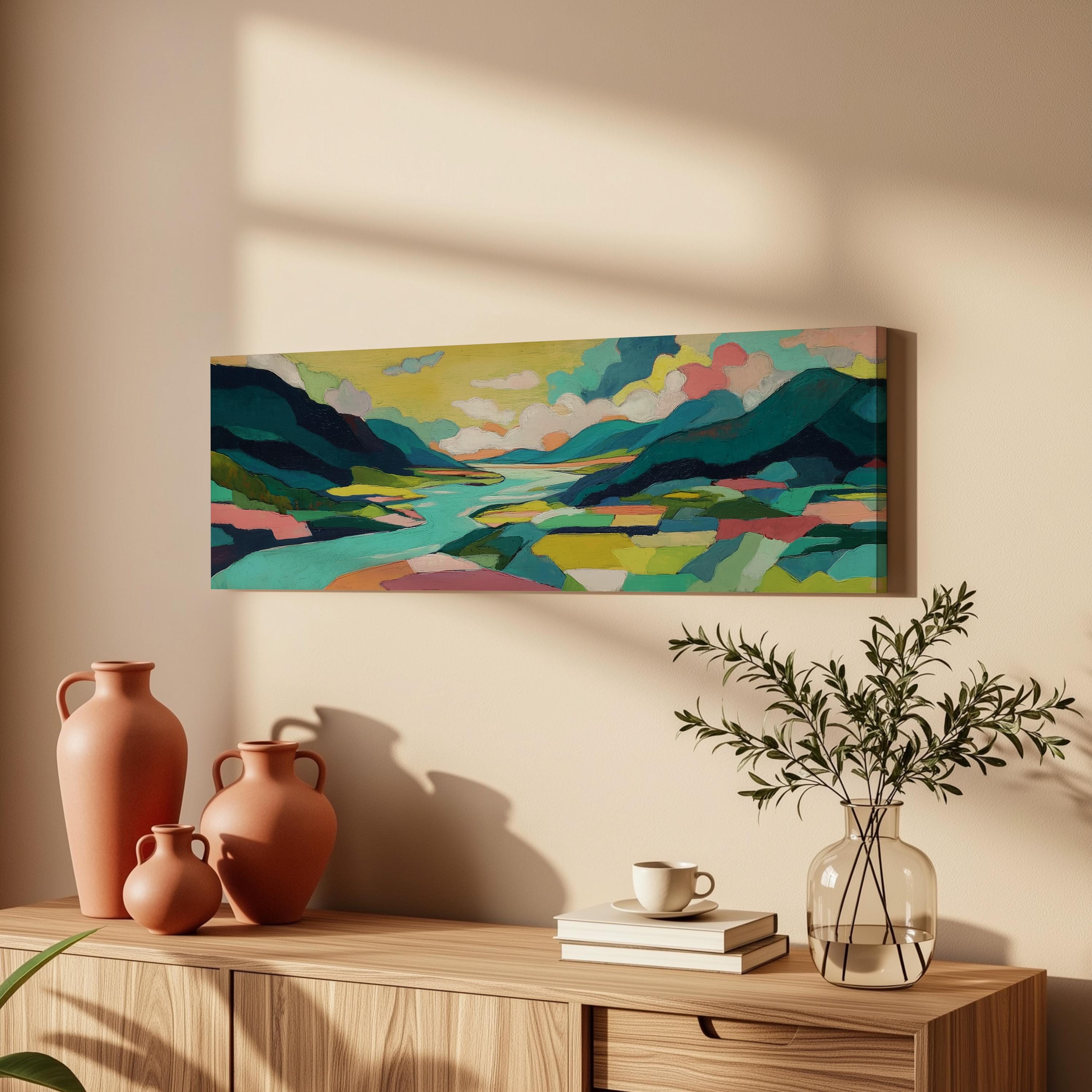 a wooden cabinet with a painting of a landscape hanging on the wall above it. The cabinet also has three orange vases and a glass vase with greenery, as well as a stack of books and a cup on the surface.