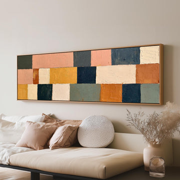 Mustard, sage, blush and navy patchwork long horizontal canvas print above a sofa in a living room