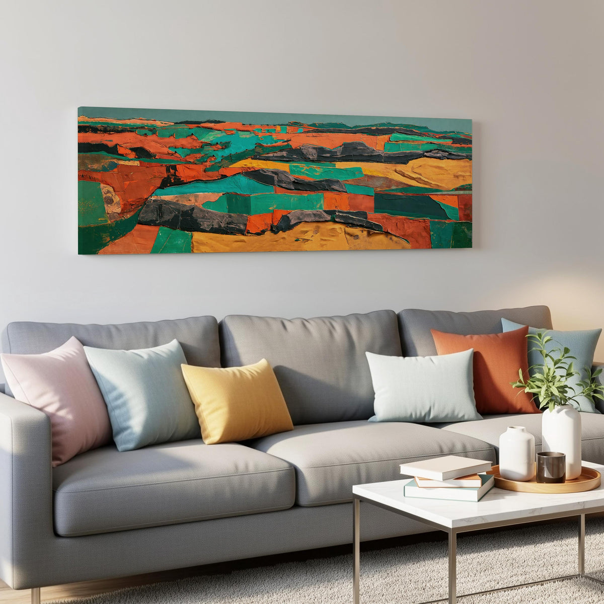Abstract patchwork terrain in orange and teal panoramic canvas print above a grey sofa in a living room
