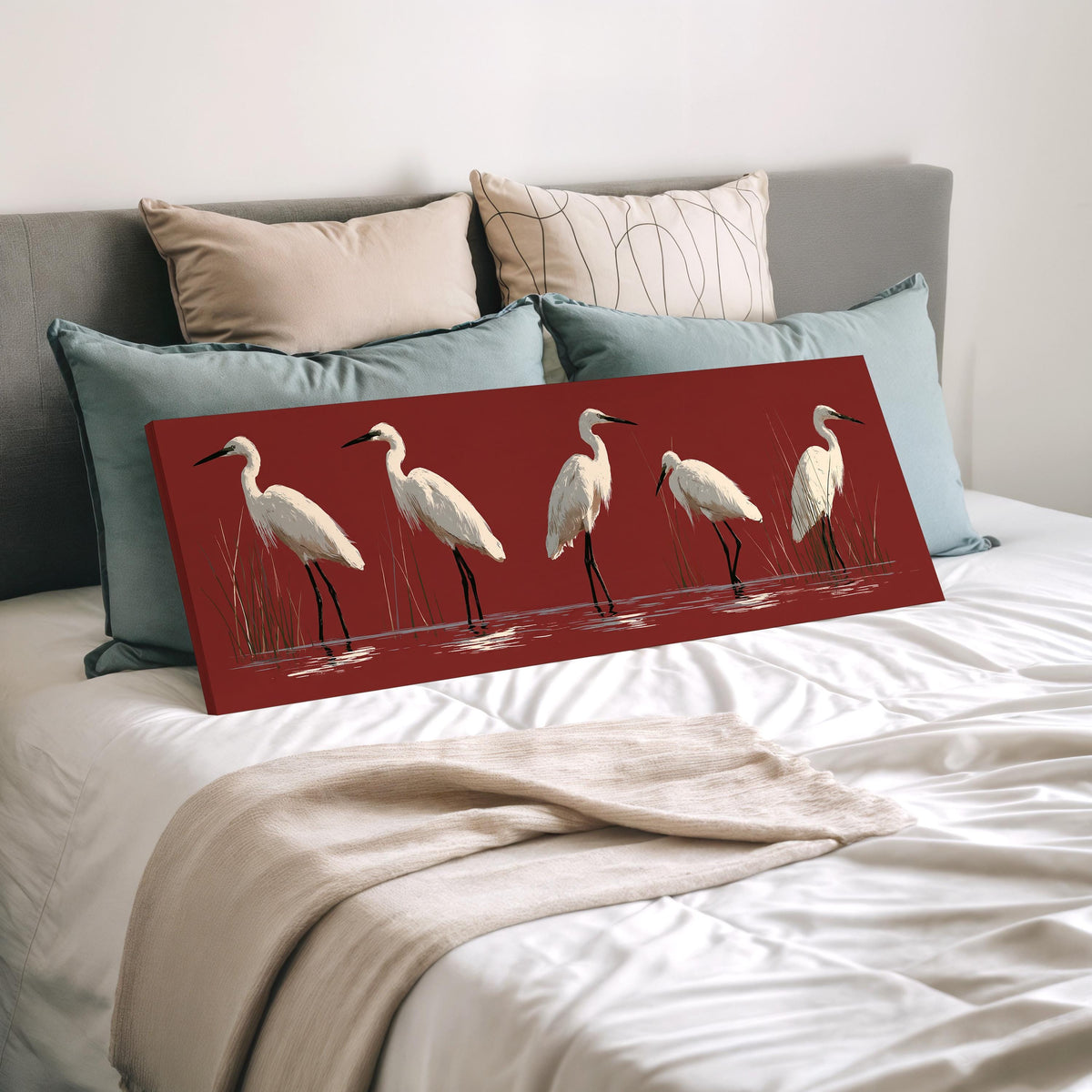White egrets wading on crimson red wide panoramic canvas print laid on a bed to show its size