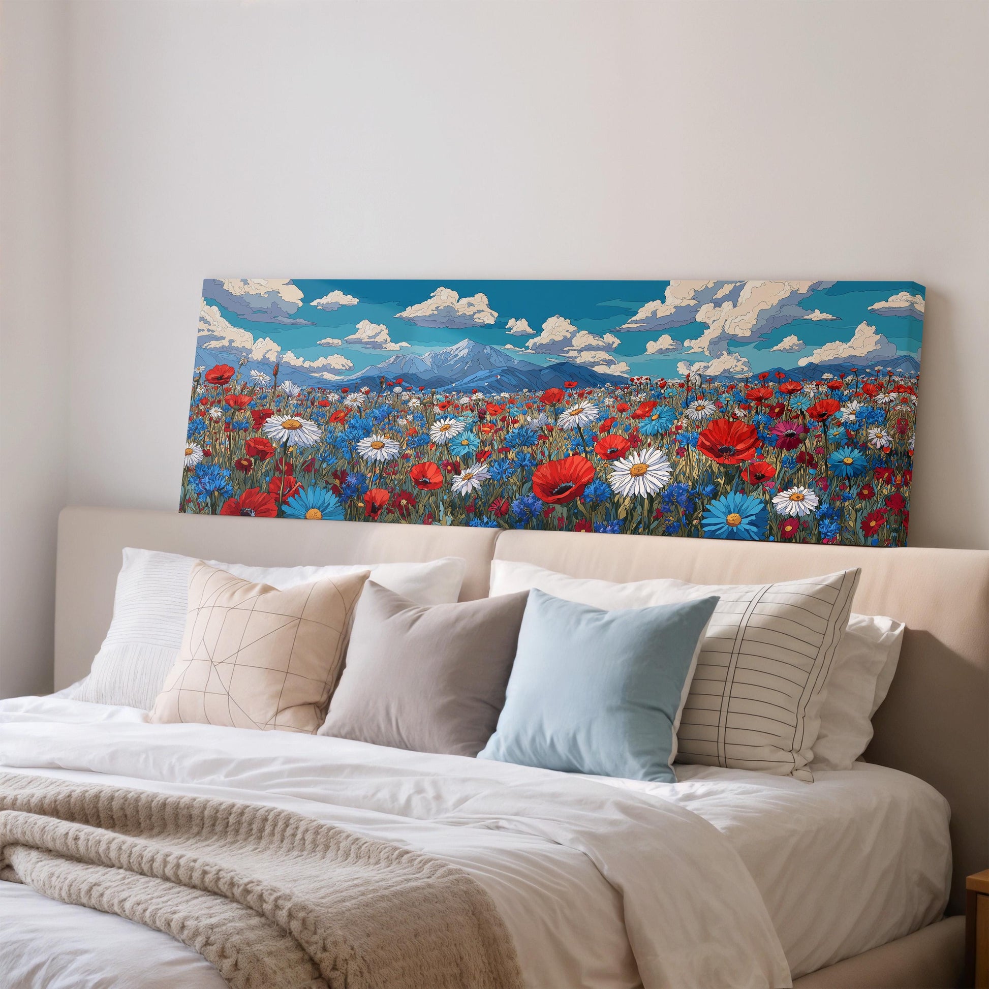 a large canvas print of a vibrant field of flowers, with mountains in the background, hanging above a bed with white pillows and a gray blanket.