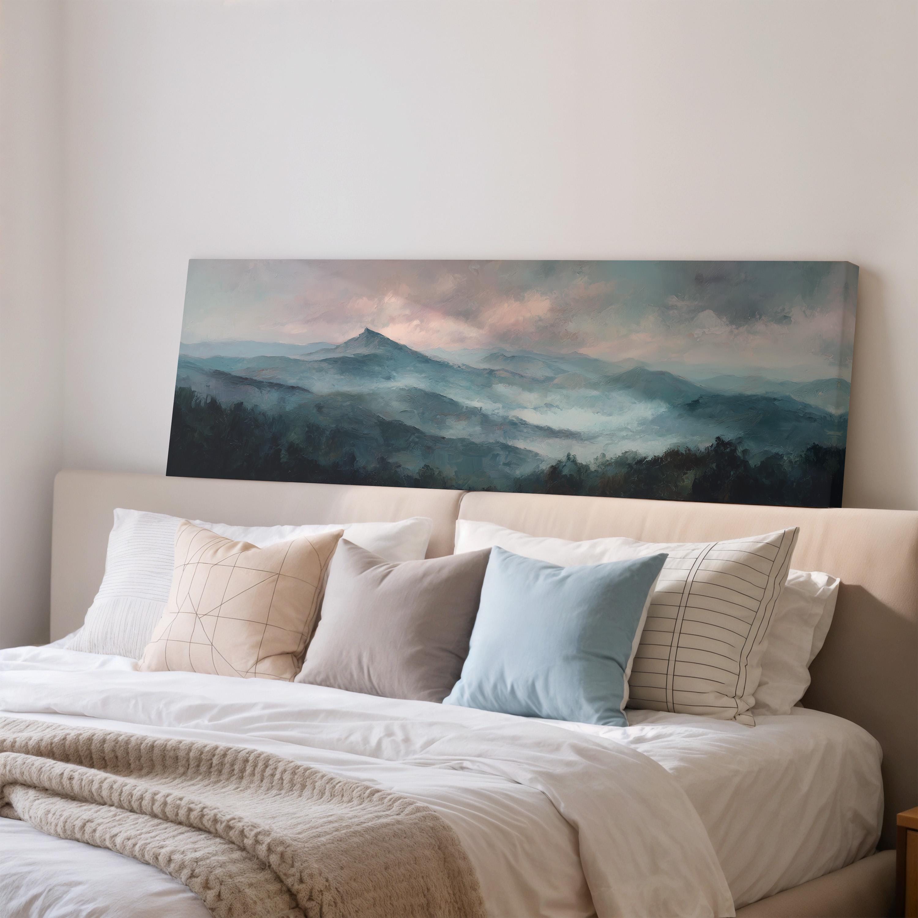 a large painting of a mountain landscape hanging on a wall above a bed with white bedding and various pillows.