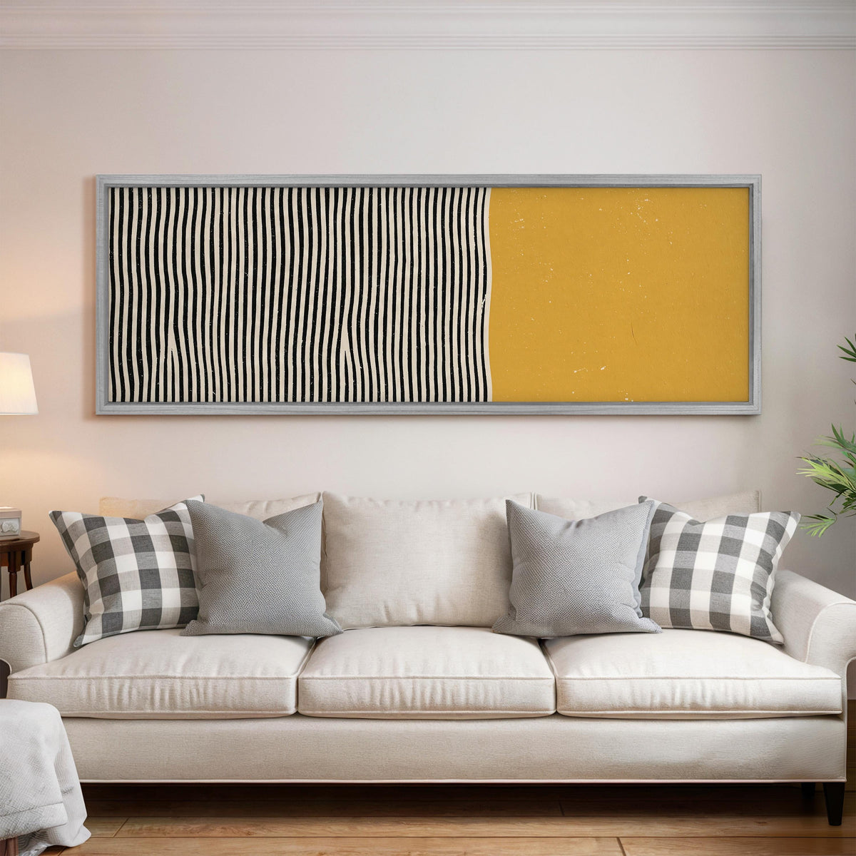 Black wavy stripes beside a mustard block panoramic canvas print above a white sofa in a bright living room