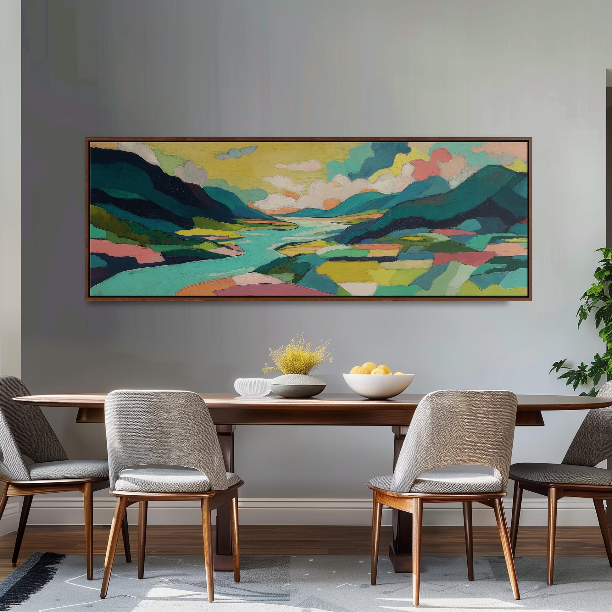 a large, colorful landscape painting hanging on a wall above a wooden dining table with four chairs. The table is set with a bowl of fruit and a vase of flowers, creating a cozy and inviting atmosphere.
