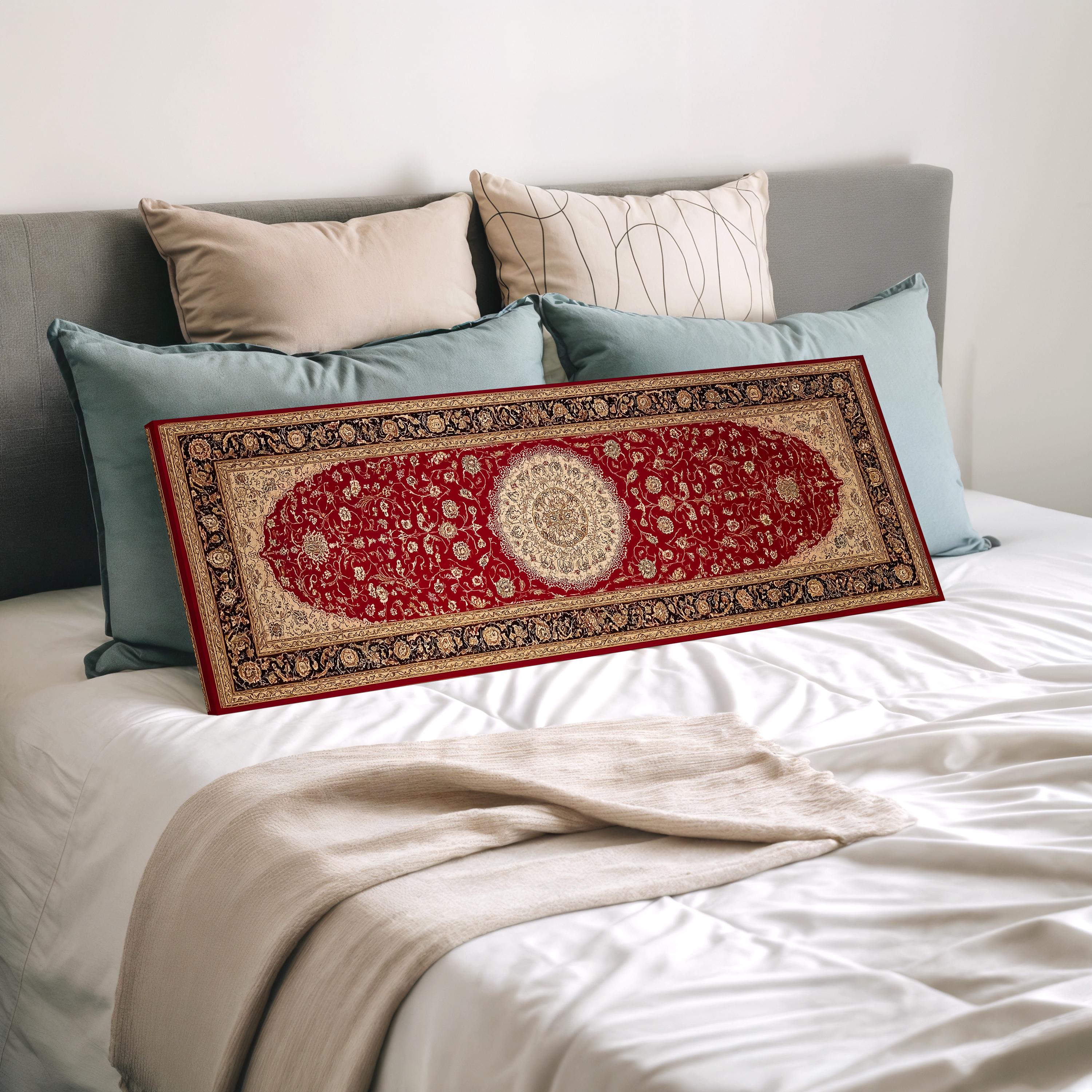 a large, ornate red and gold rug placed on a bed with a white comforter and several pillows.