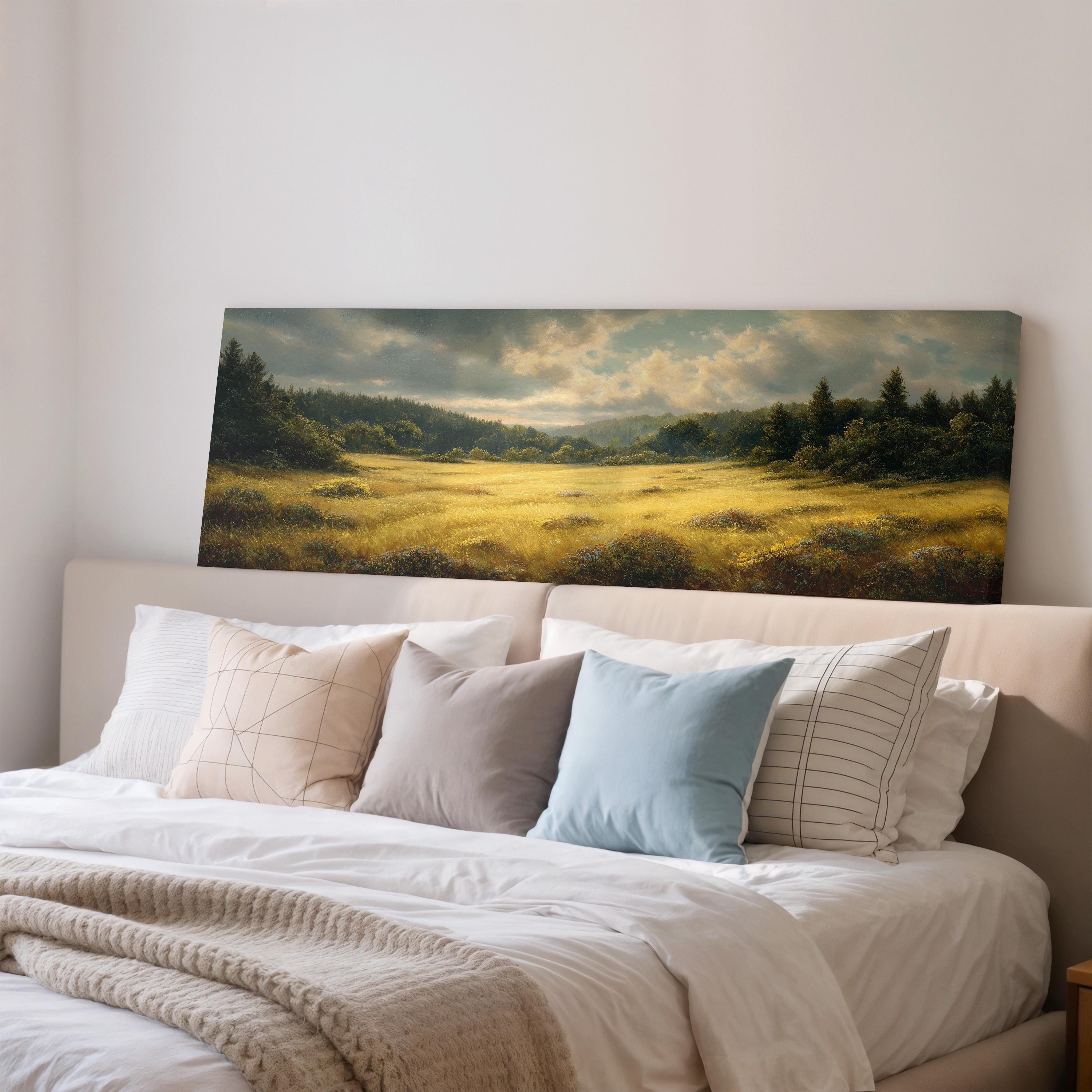 a large landscape painting hanging on a wall above a bed with white pillows and a gray blanket.