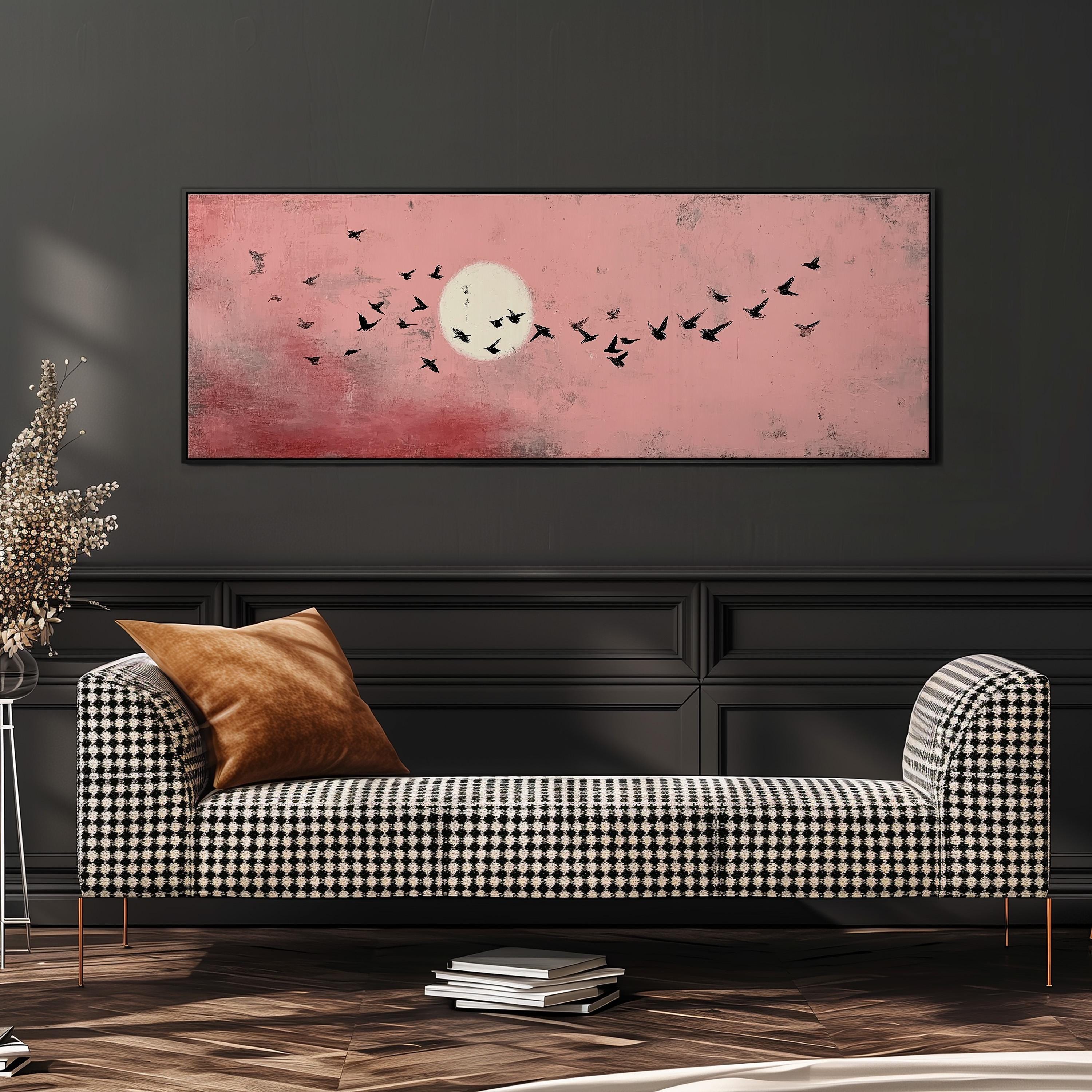 a checkered sofa with a brown throw pillow, set against a dark wall with a large framed painting depicting a flock of birds flying against a pink and red sky.