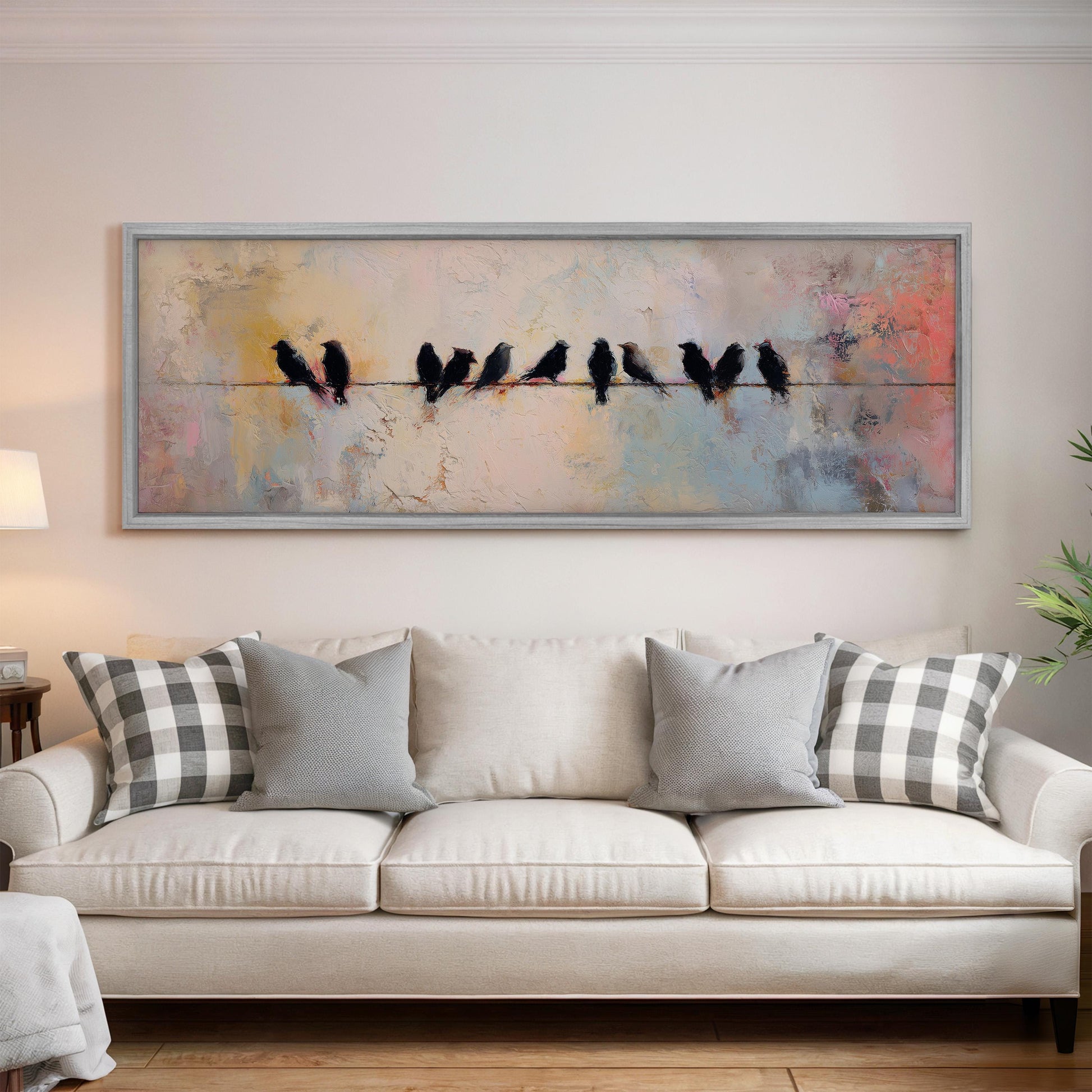 a large painting of a group of birds perched on a wire, hanging above a white couch in a living room setting.
