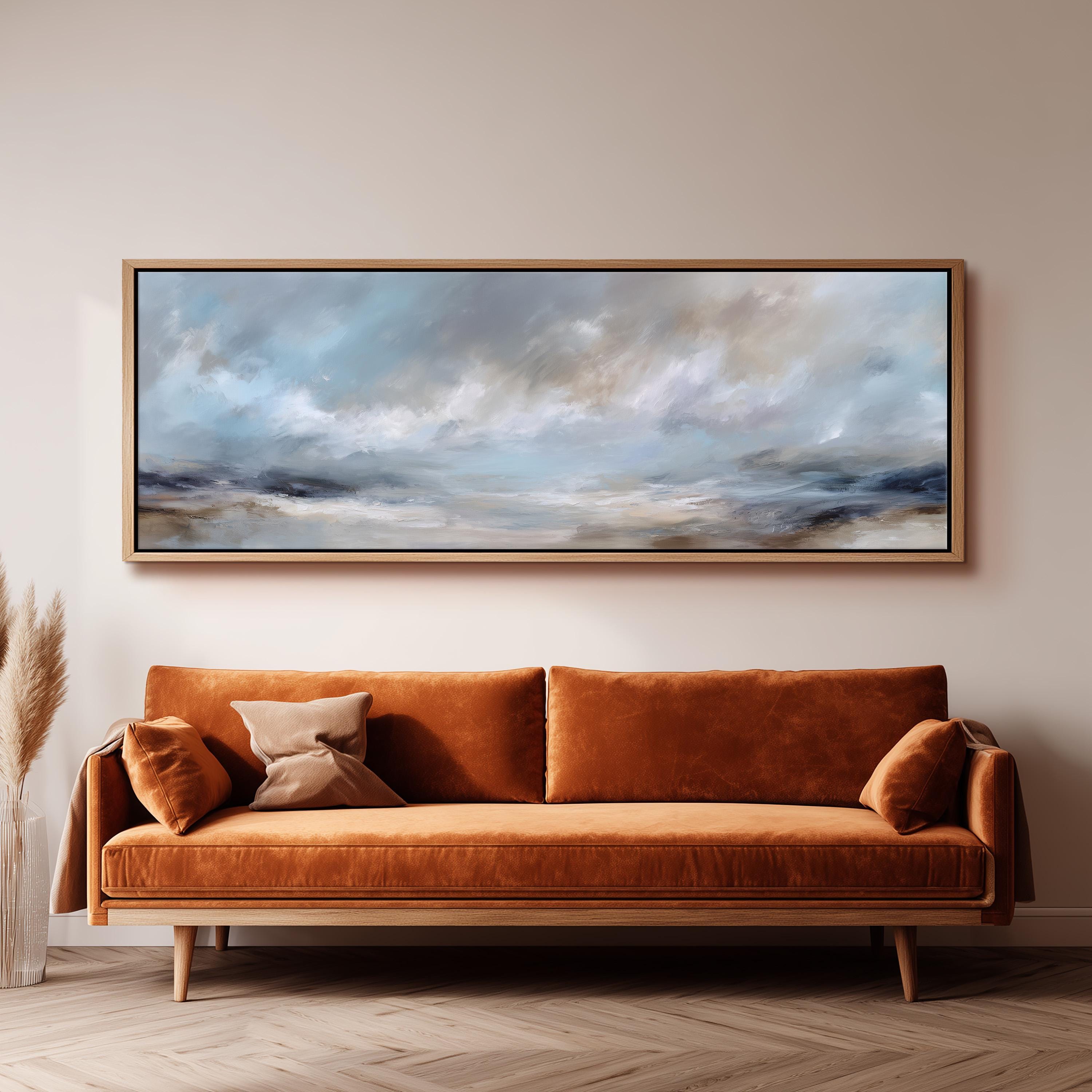 a large, rectangular painting hanging on a wall above a brown sofa with orange cushions.