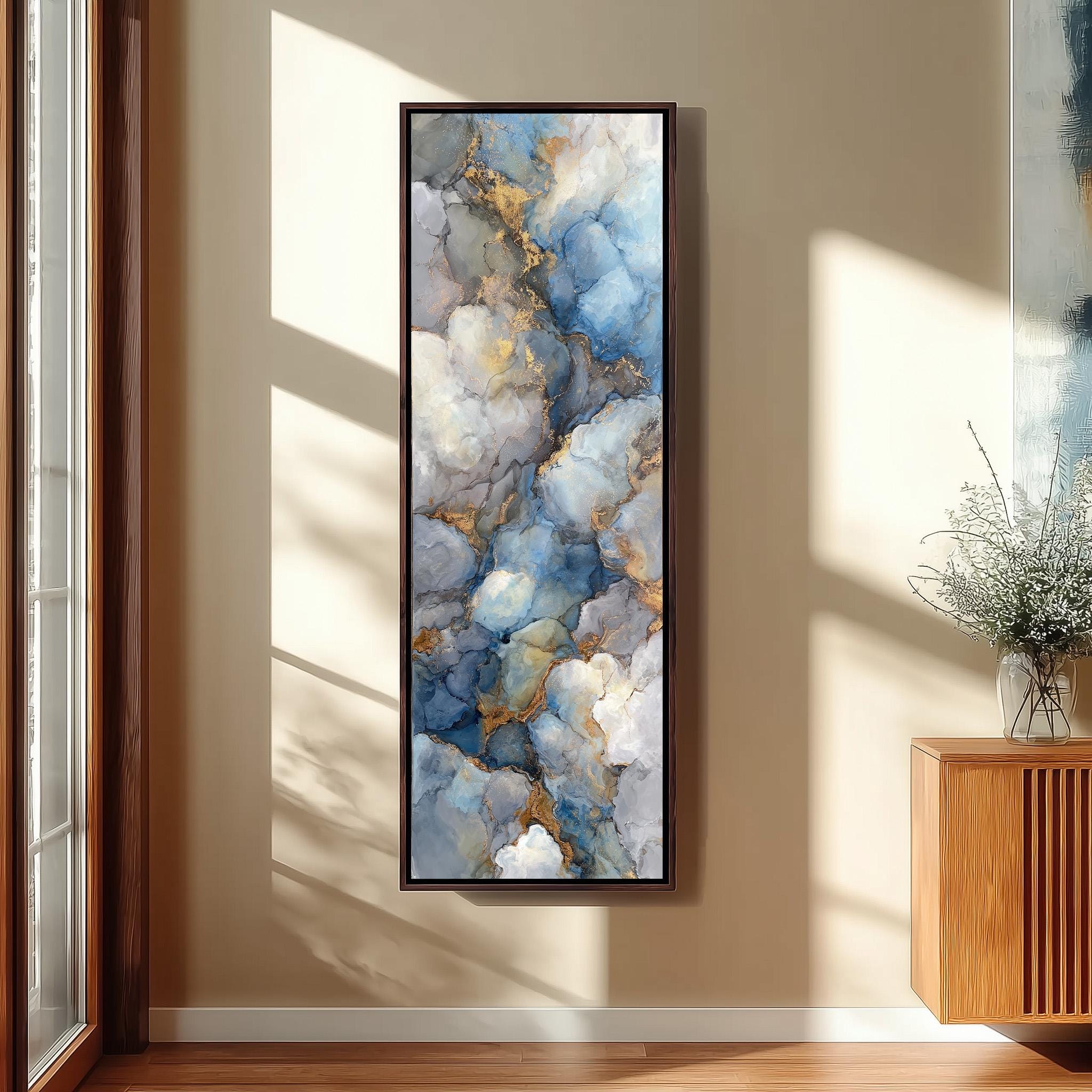 a large, framed painting hanging on a wall in a room with a wooden floor and a window.