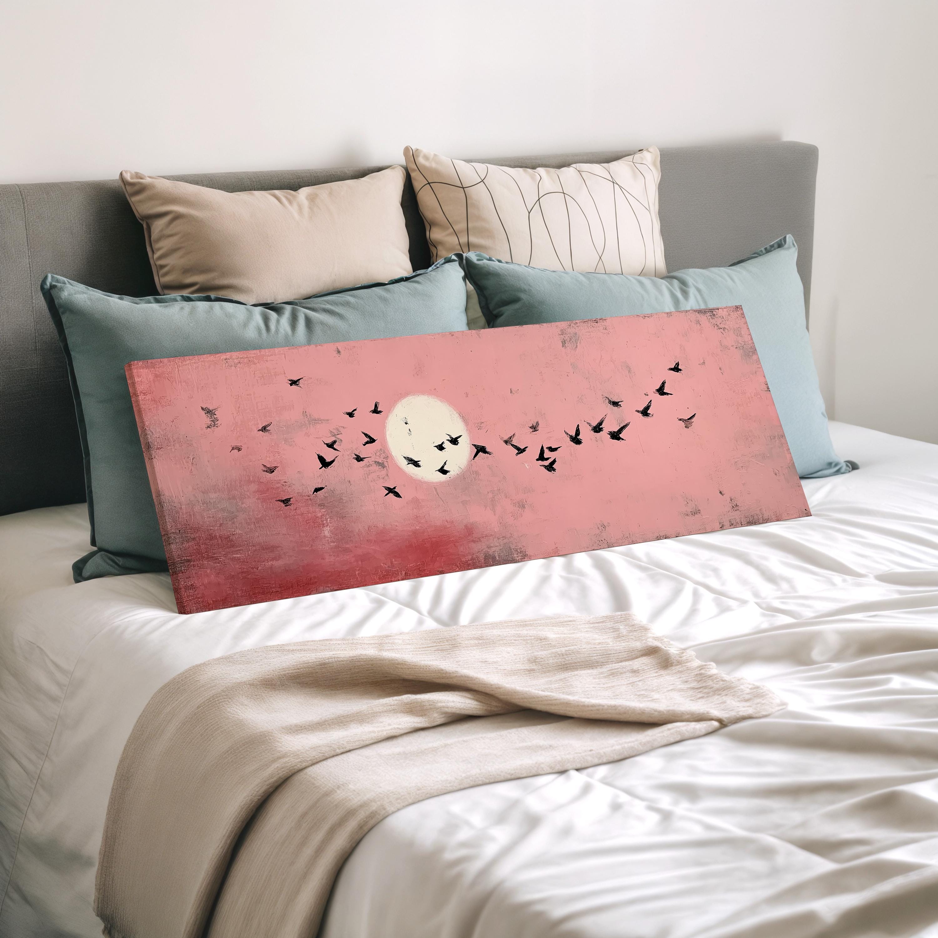 a large, vibrant pink canvas with a flock of birds depicted on it, resting on a bed with white sheets and pillows.