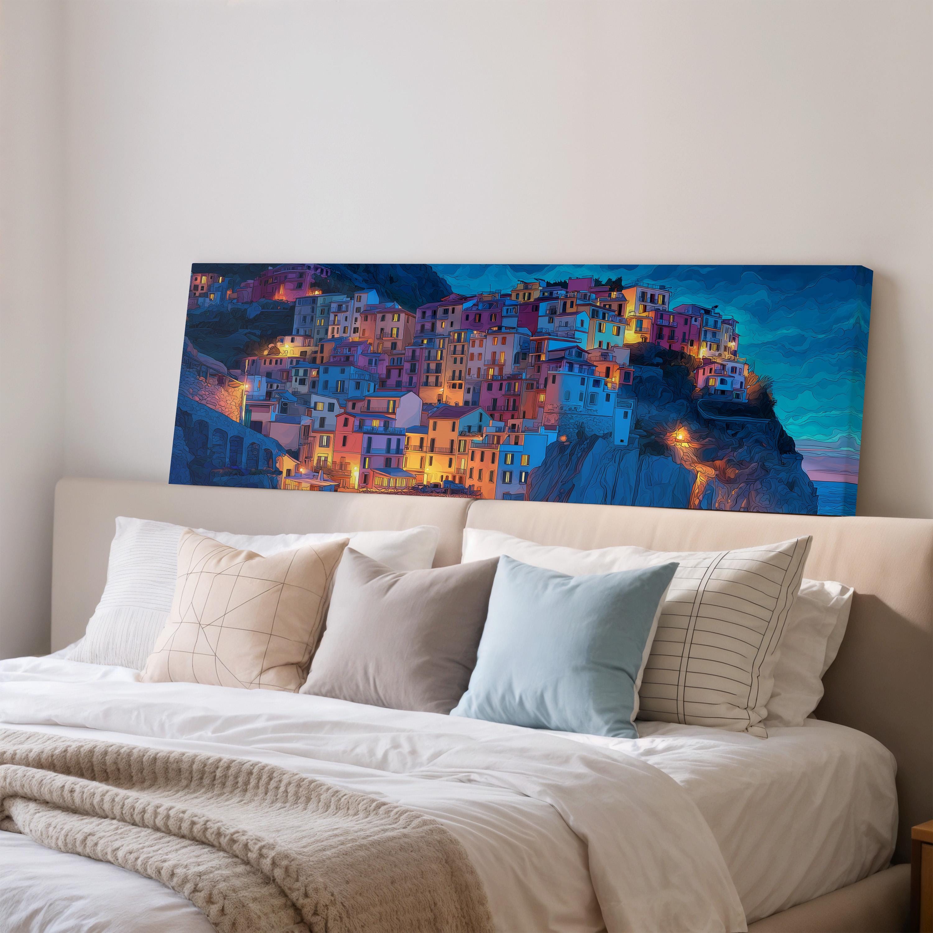 a large, colorful painting of a cityscape on the wall above a bed with white pillows and a gray blanket.
