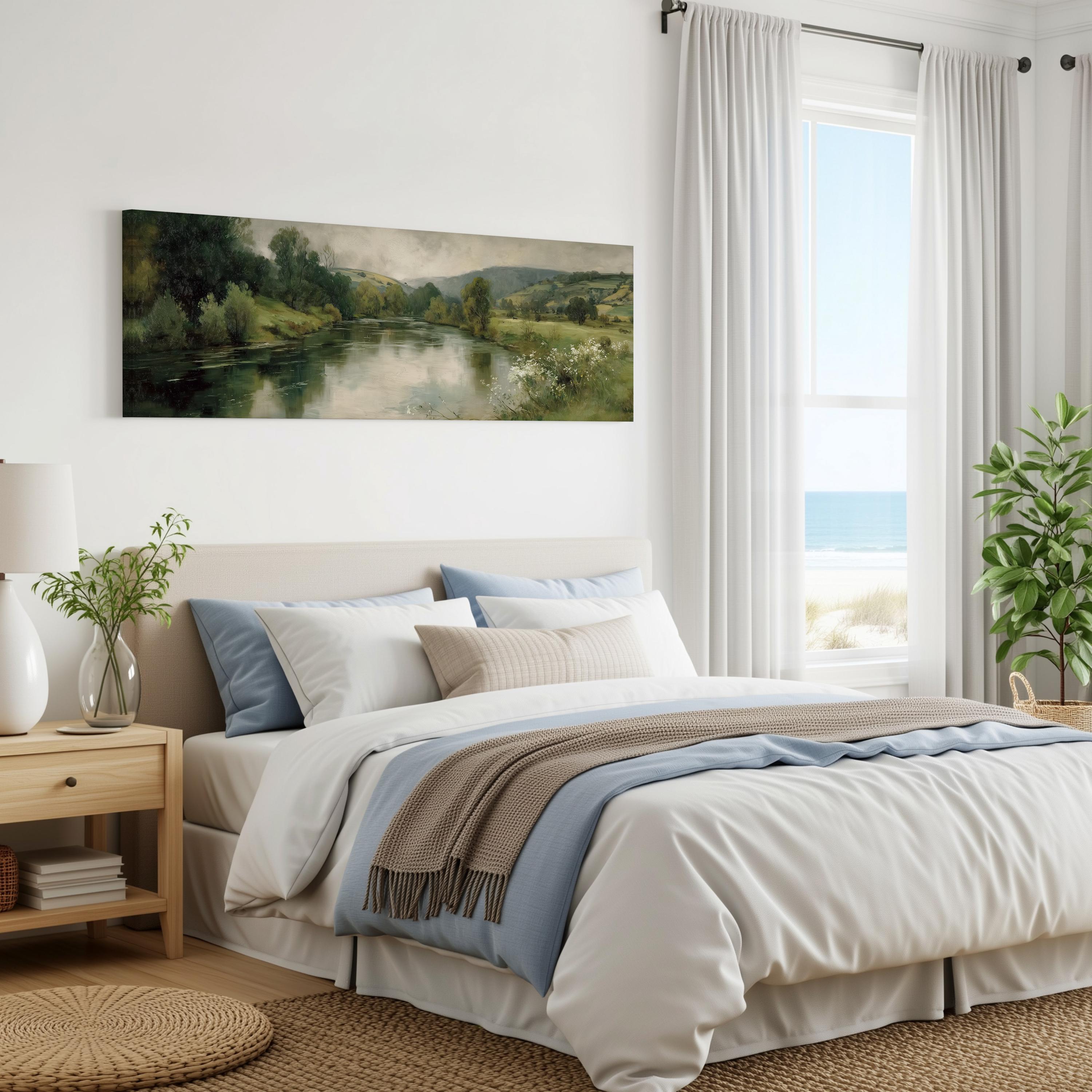 a serene bedroom with a large bed, a painting of a river and trees on the wall, and a window overlooking the ocean.