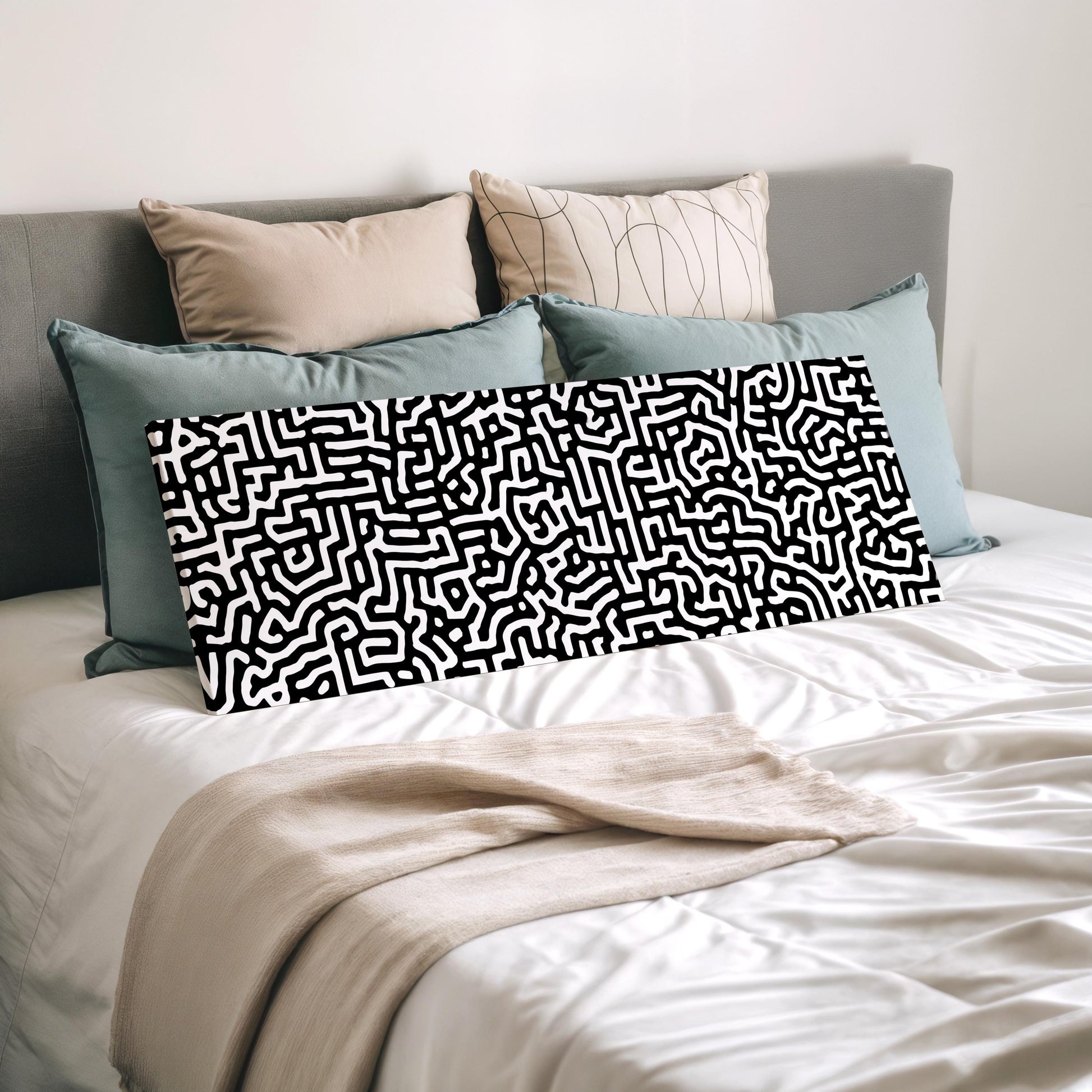 a bed with a white comforter and a black and white patterned pillow.