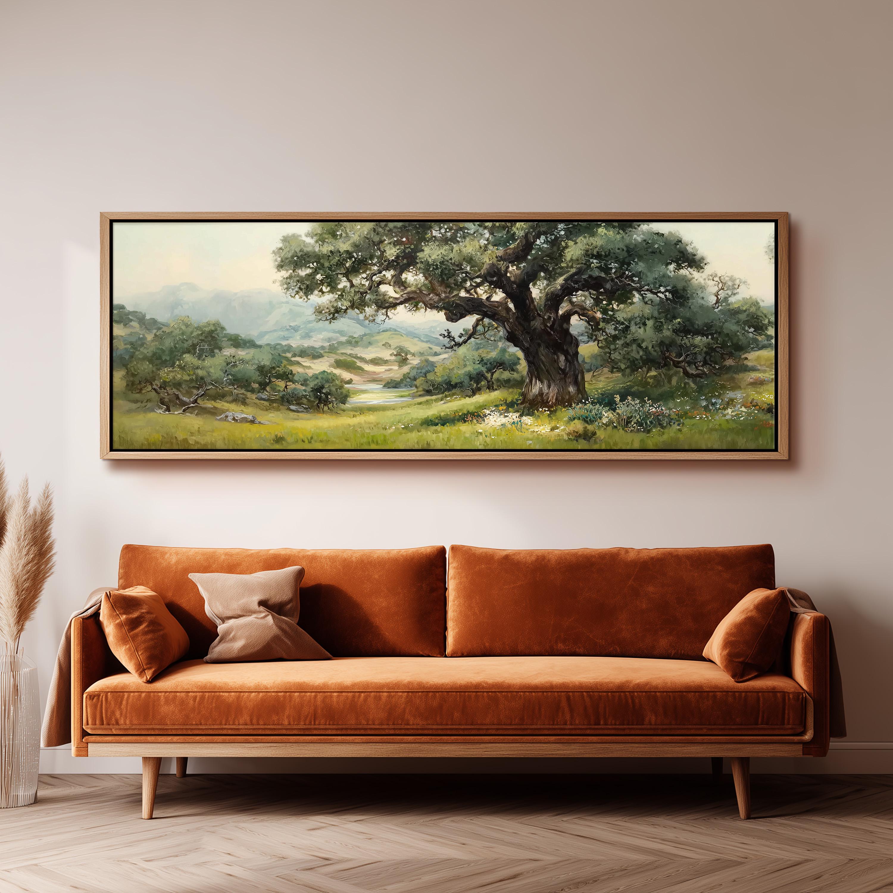 a large painting of a lush green landscape hanging on a wall above a brown sofa with orange cushions.