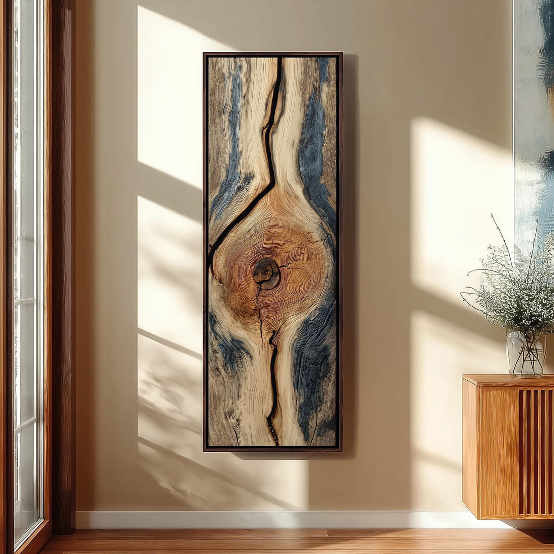 a large, abstract painting of a tree trunk with a unique, textured pattern. The painting is hanging on a wall, and there is a vase of flowers placed next to it.