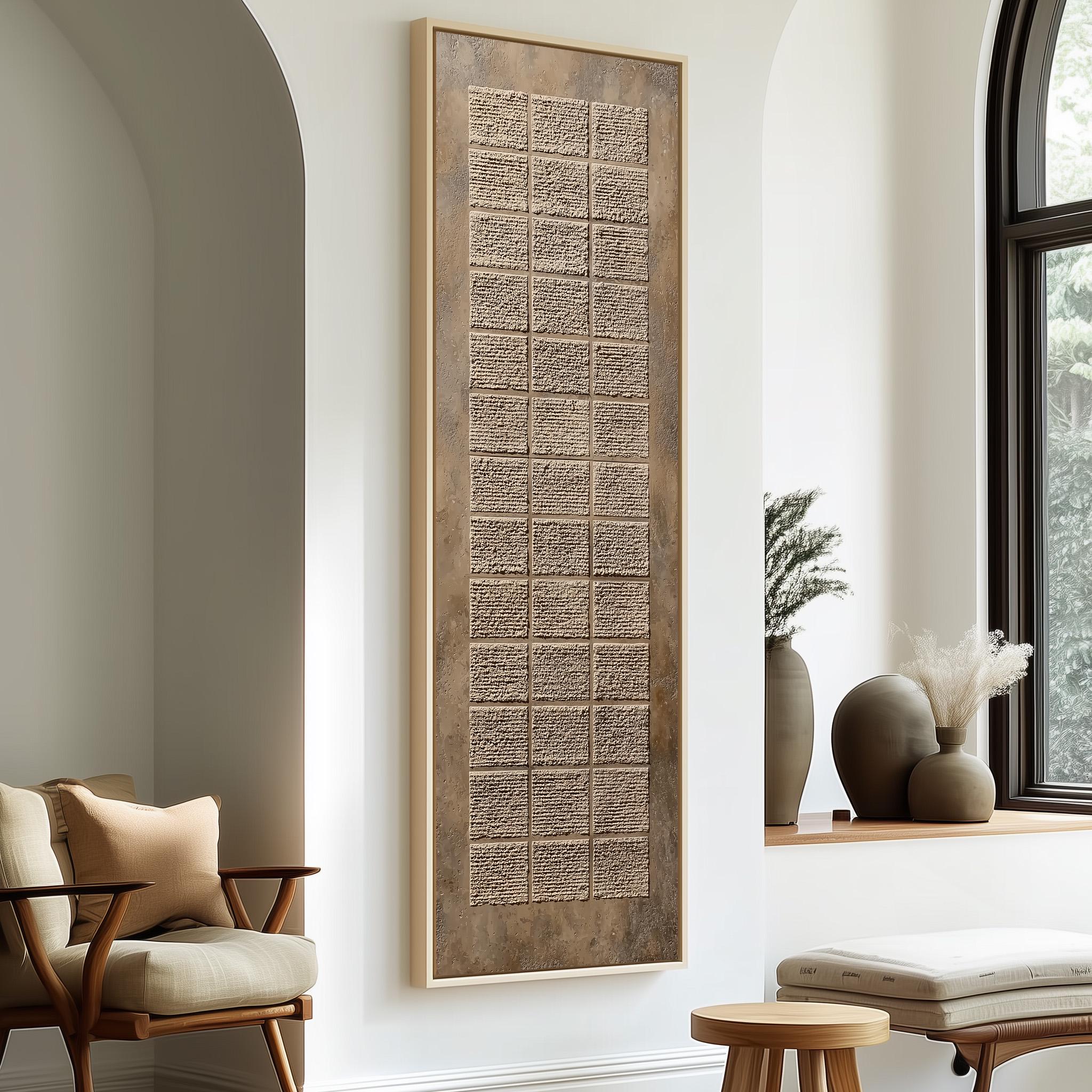 a modern living room with a large, rectangular wall art piece that has a textured, beige-colored design. The room is furnished with a wooden chair, a small table, and a window with a plant on the sill.