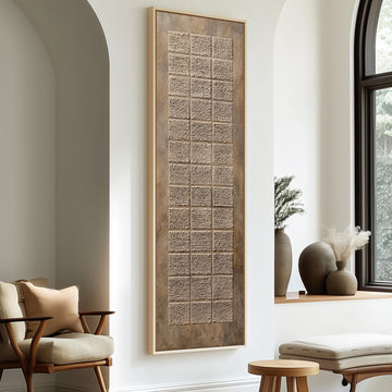 a modern living room with a large, rectangular wall art piece that has a textured, beige-colored design. The room is furnished with a wooden chair, a small table, and a window with a plant on the sill.
