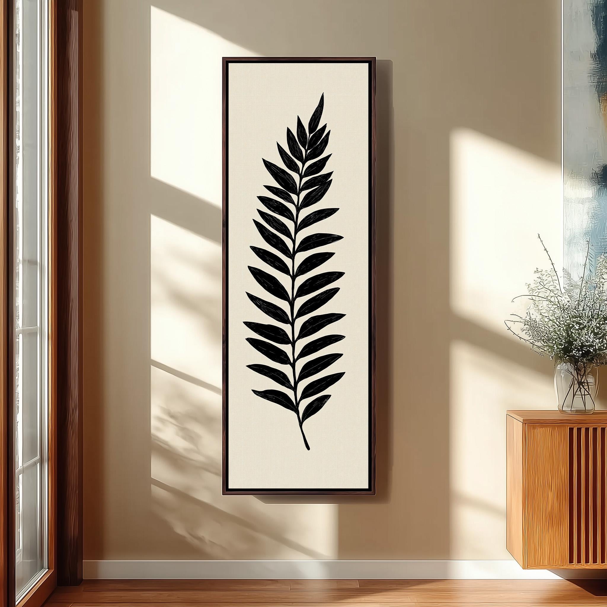 a framed artwork of a leaf on a wall, with a wooden cabinet and a vase of flowers to the right side of the frame.