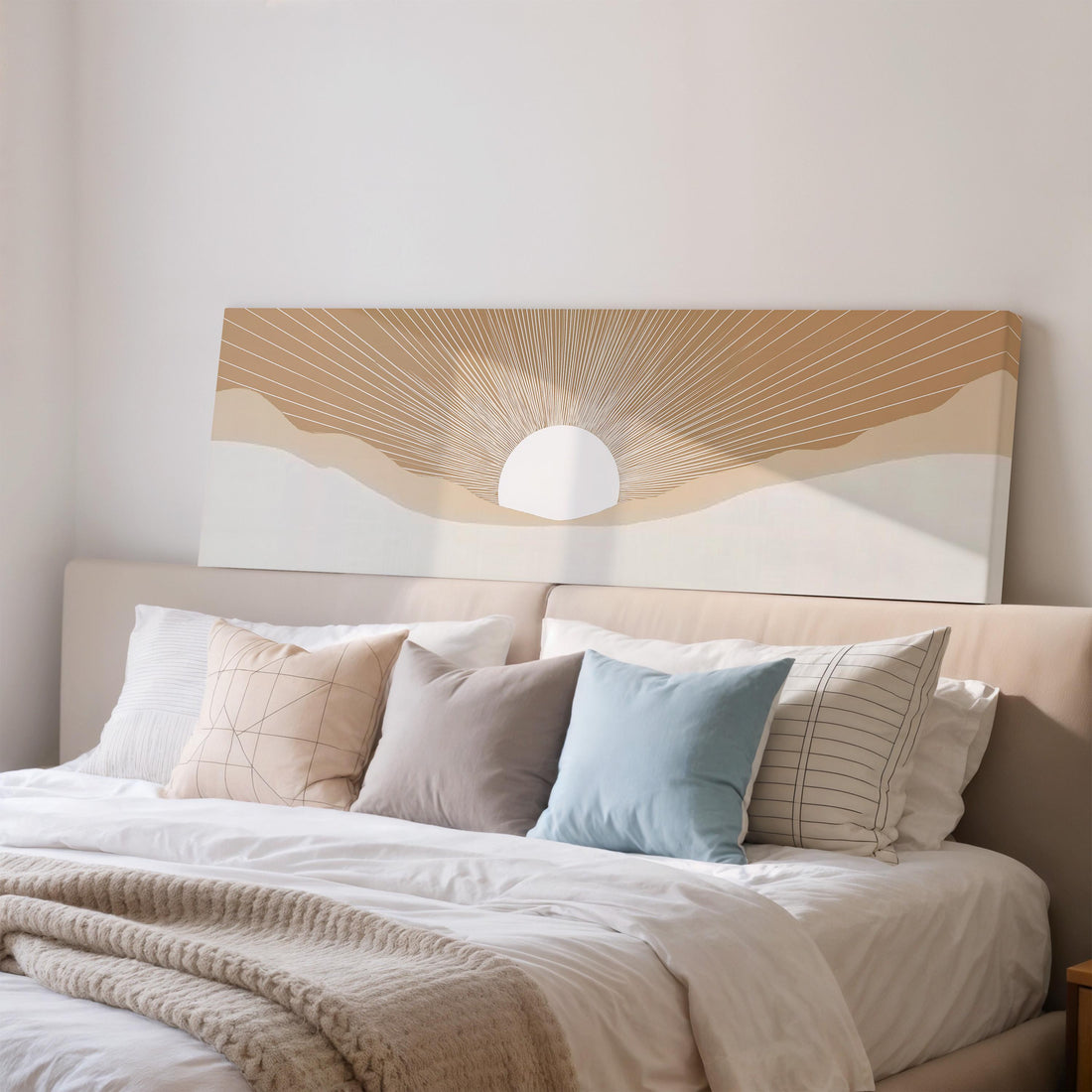 a large, rectangular, framed artwork depicting a sun-like design on a wall above a brown sofa with two pillows.