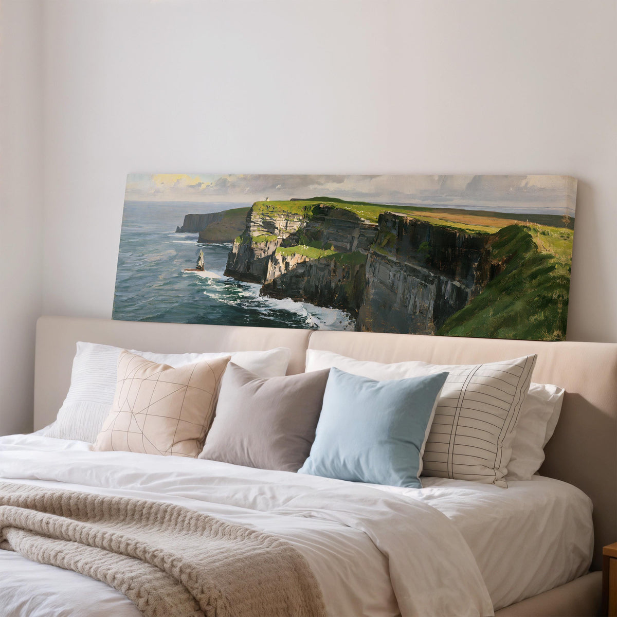Sunlit sea cliffs with a sea stack wide panoramic canvas print above a bed in a bedroom