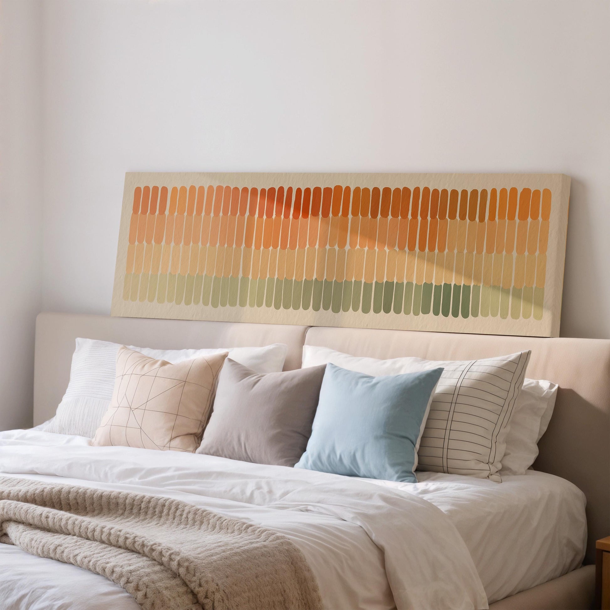 a cozy bedroom with a large bed adorned with a variety of pillows in different colors and patterns. Above the bed, there is a large abstract painting or artwork featuring vertical lines in various shades of orange, green, and blue.