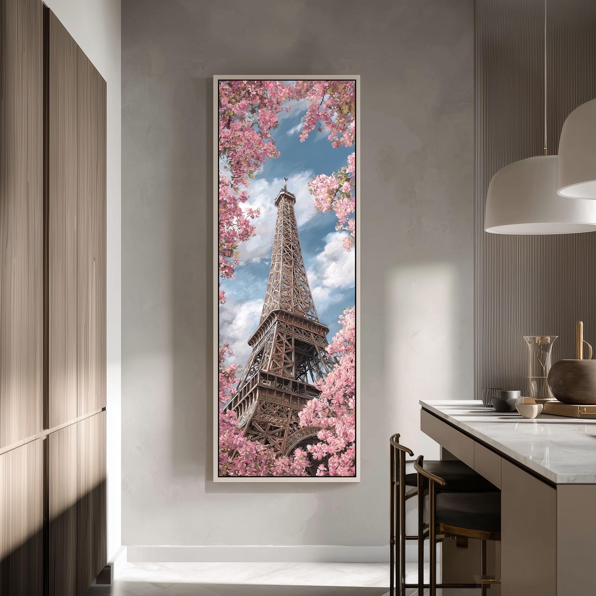 a large framed picture of the Eiffel Tower, surrounded by pink cherry blossoms, hanging on a wall in a modern kitchen.