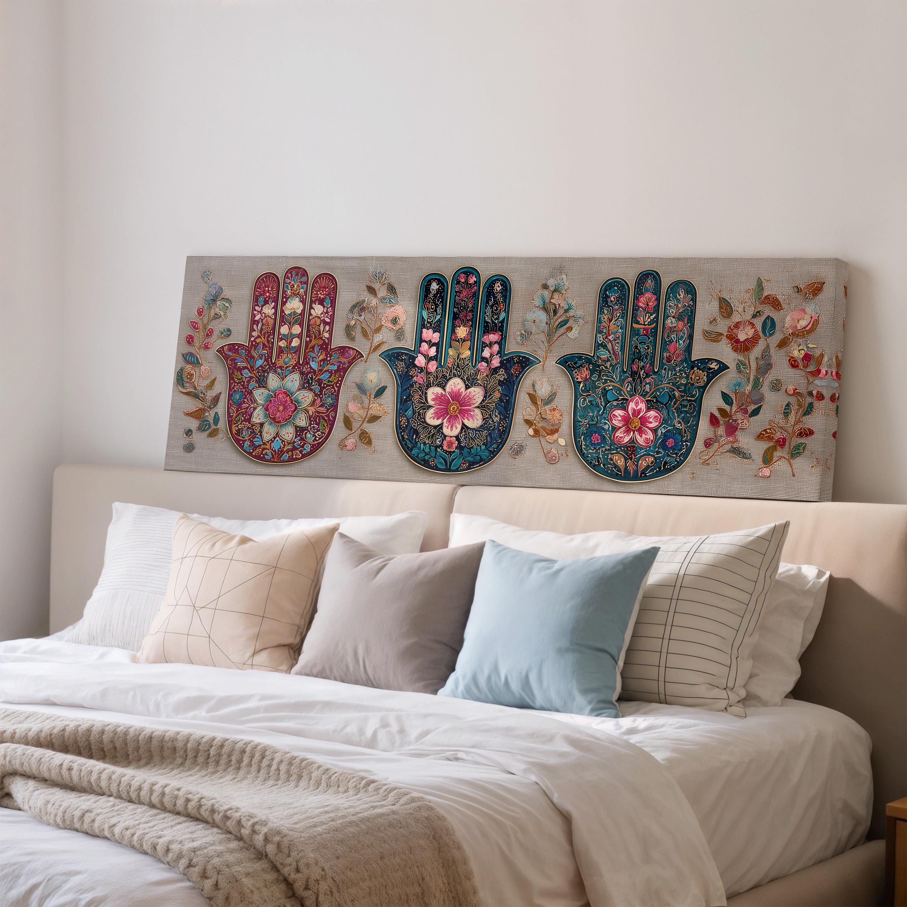 a large, colorful painting of three hand-painted floral designs on a wall above a bed with white bedding and pillows.