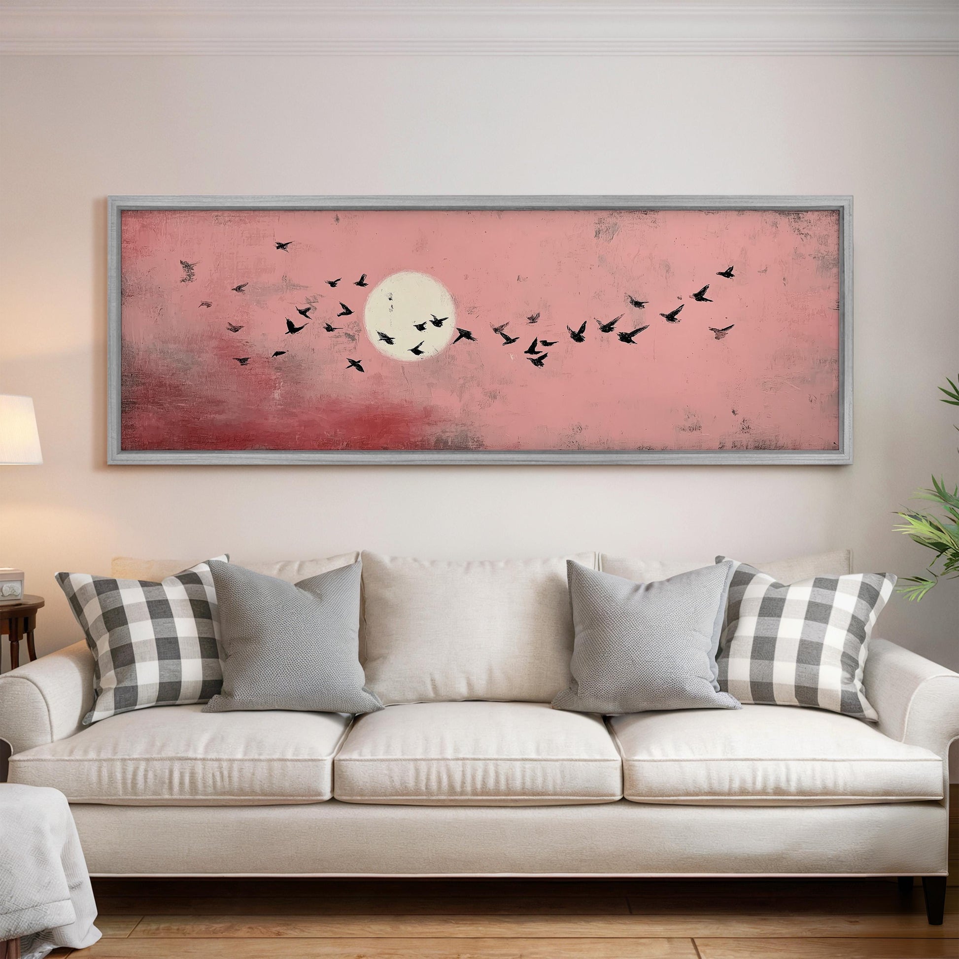 a large framed painting of a flock of birds flying against a pink sky with a full moon.