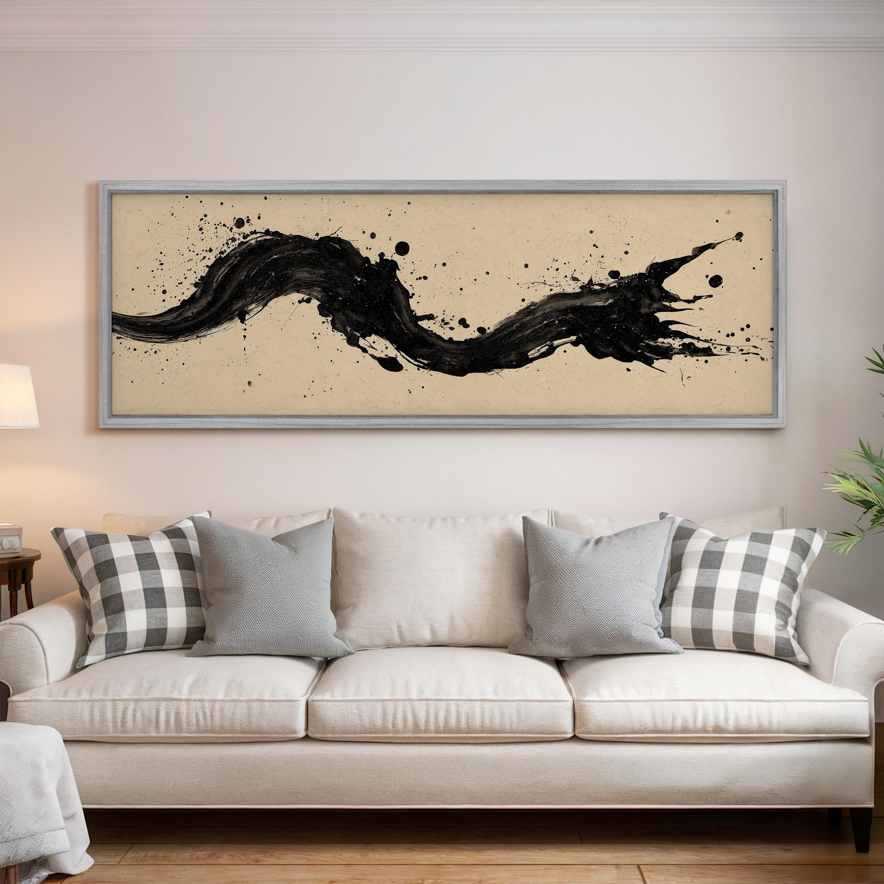 a large, abstract painting hanging on a wall above a white couch with gray and white plaid throw pillows.