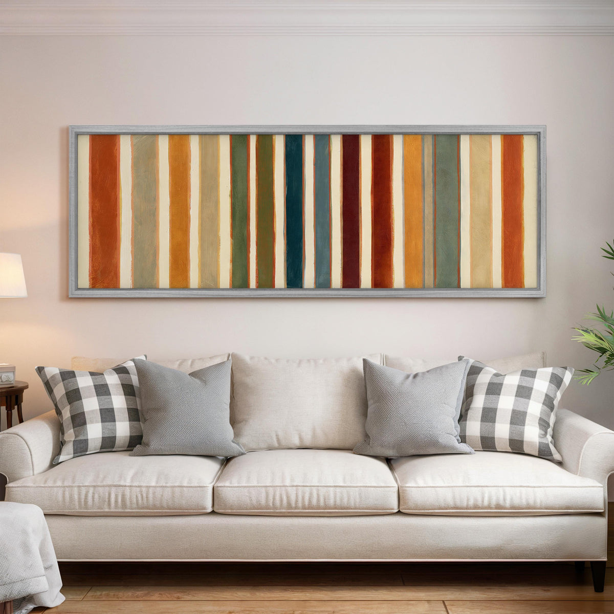 Rust, sage, maroon and teal stripes panoramic canvas print above a white sofa in a bright living room