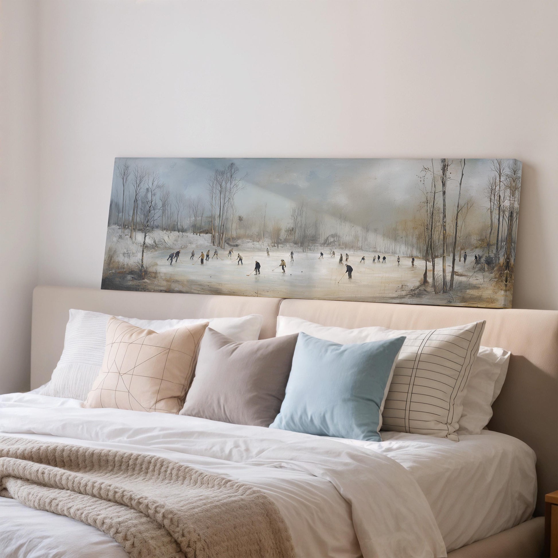 a large painting of a snowy landscape with people skiing on a frozen lake, displayed on a wall above a bed with white bedding and pillows.