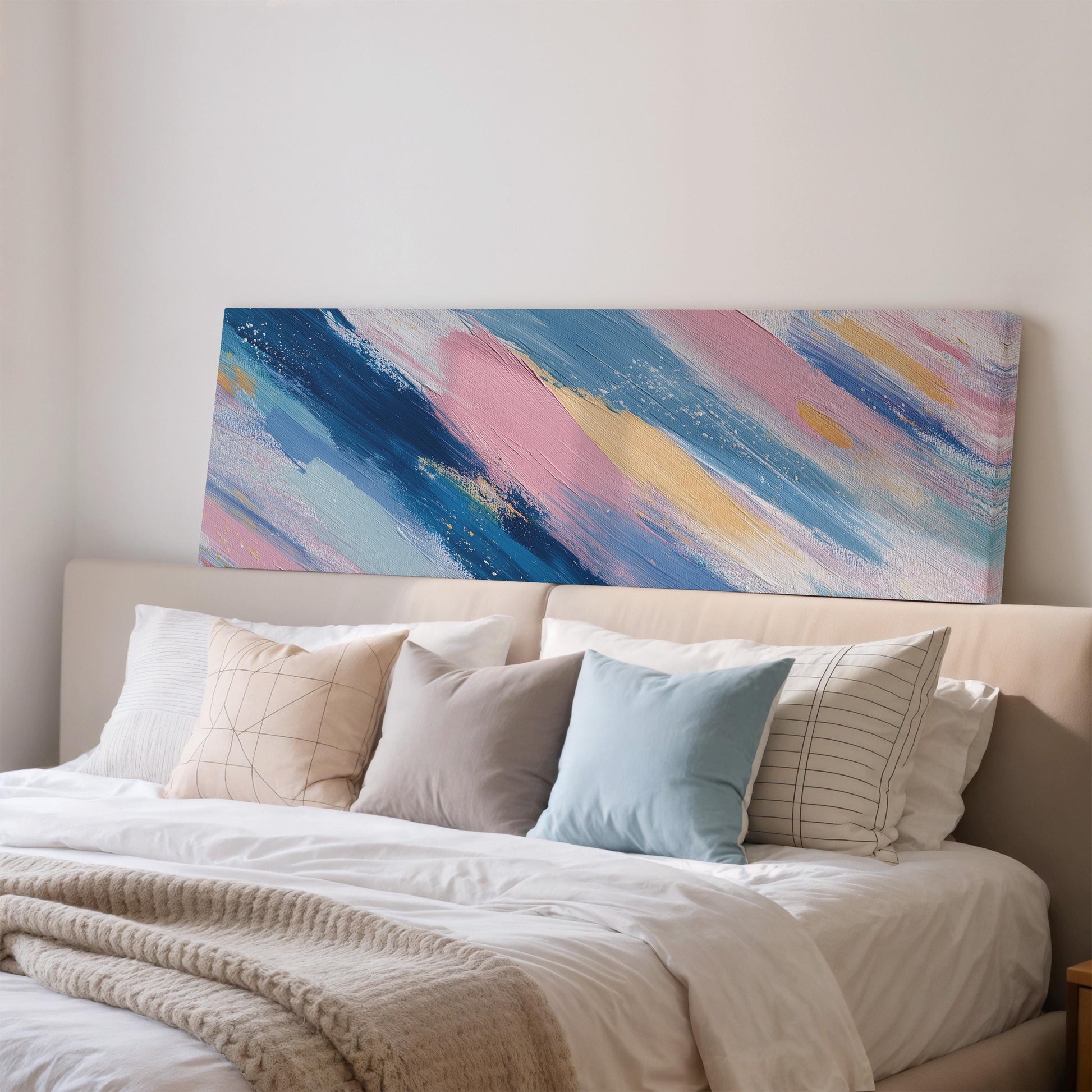 a large abstract painting hanging on a wall above a bed with white pillows and a gray blanket.