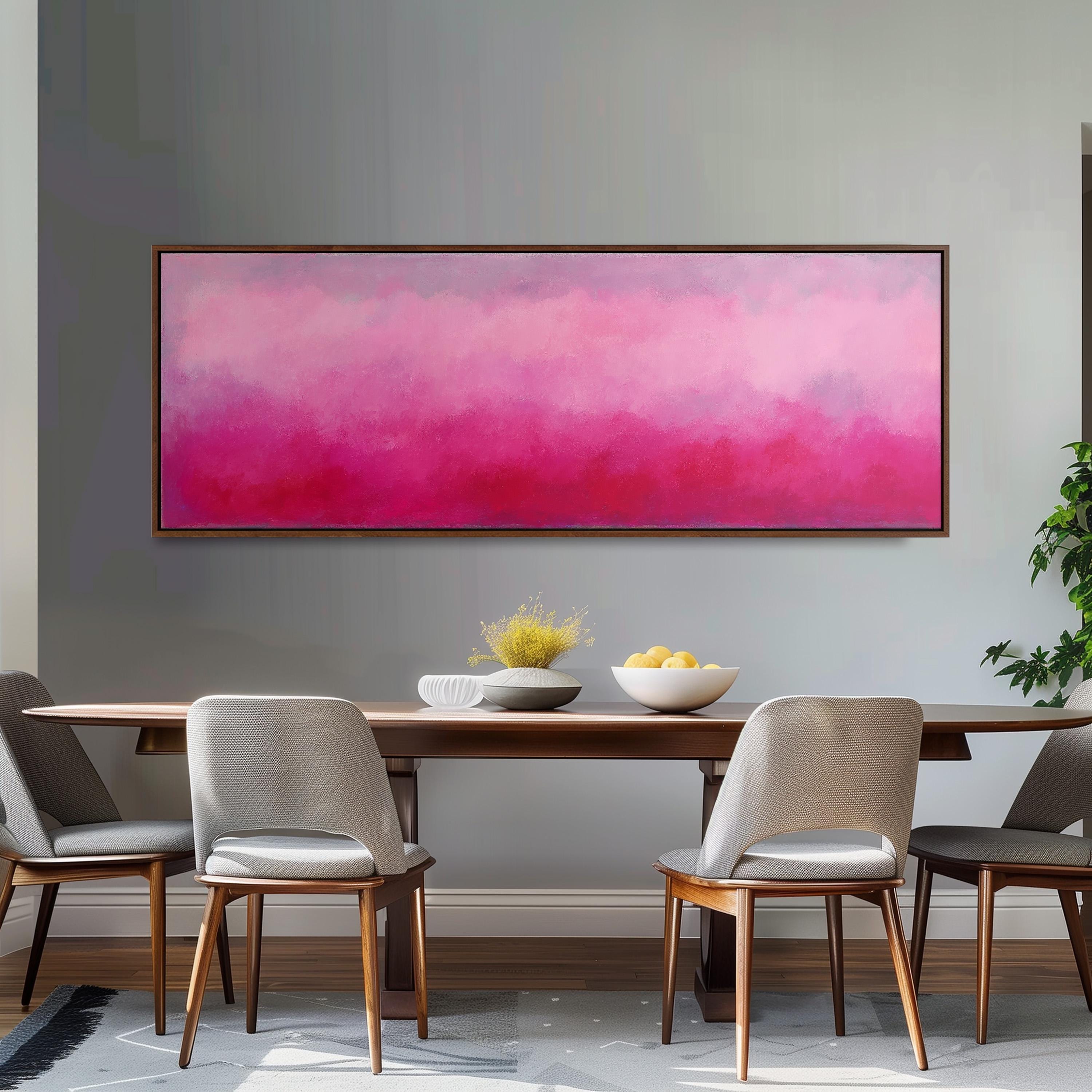 a dining room with a wooden table and four chairs. Above the table, there is a large painting with a pink and purple gradient background. On the table, there is a bowl of fruit and a vase of flowers.